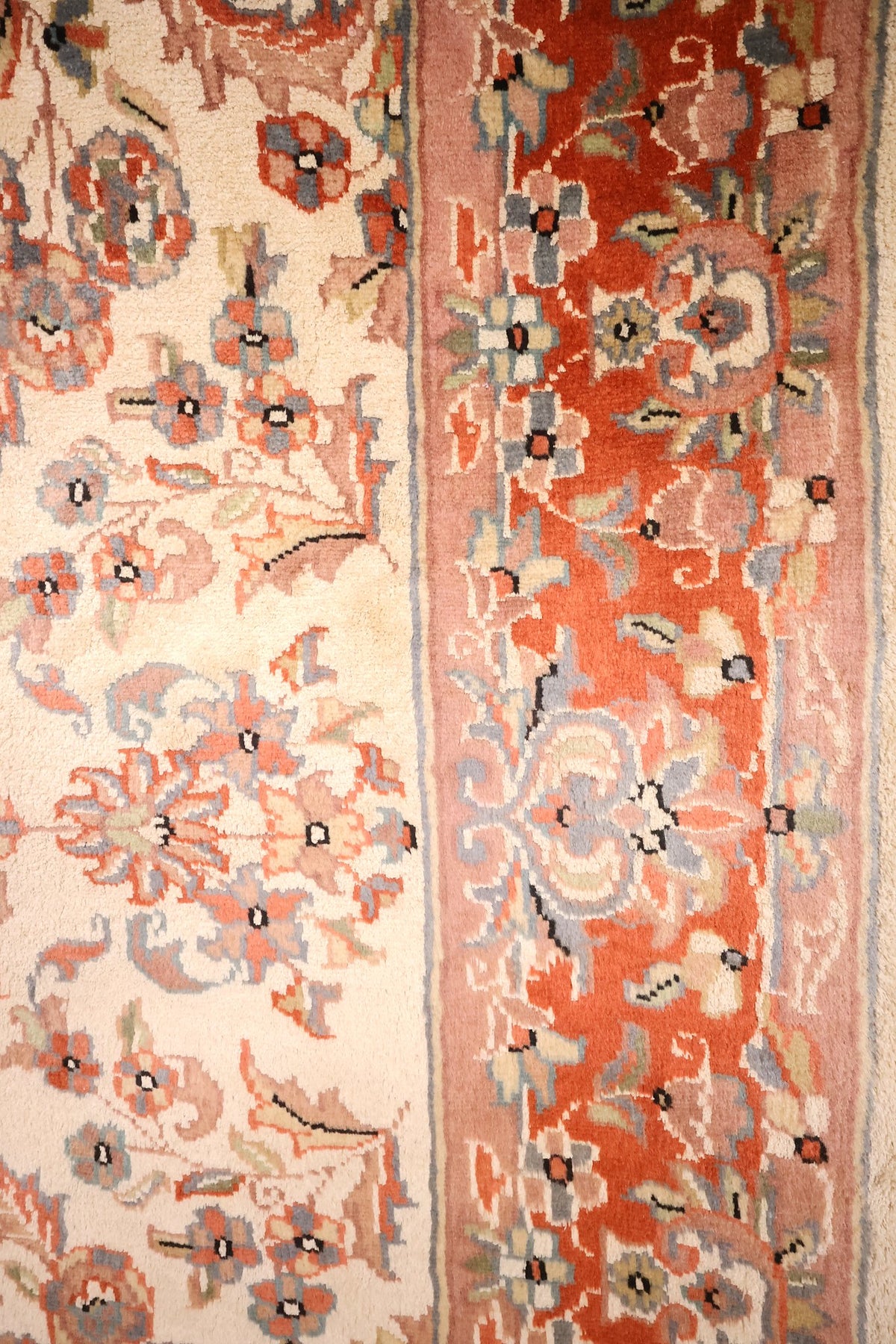 Bordure rouge brique à rinceaux fleuris et filets rose du tapis PLS