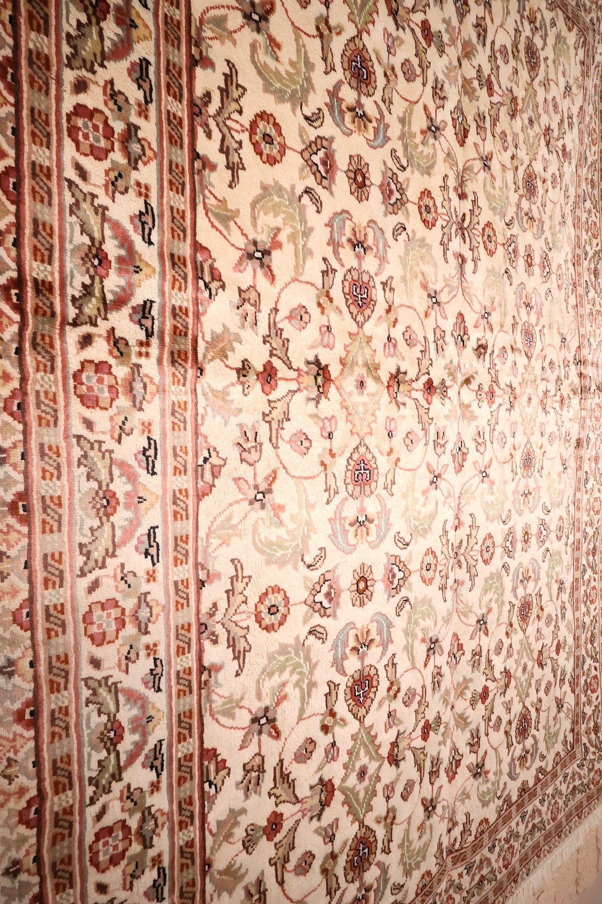 Vue de biais du tapis PLS : champ ivoire et encadrement à tiges rouges