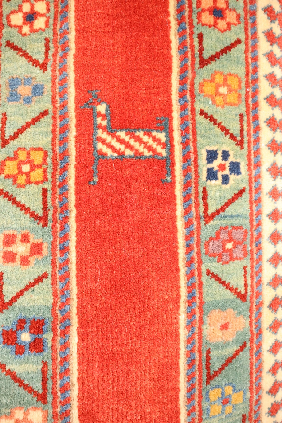 Bordure vert d'eau à triangles et fleurettes, avec animal stylisé sur le champ rouge uni