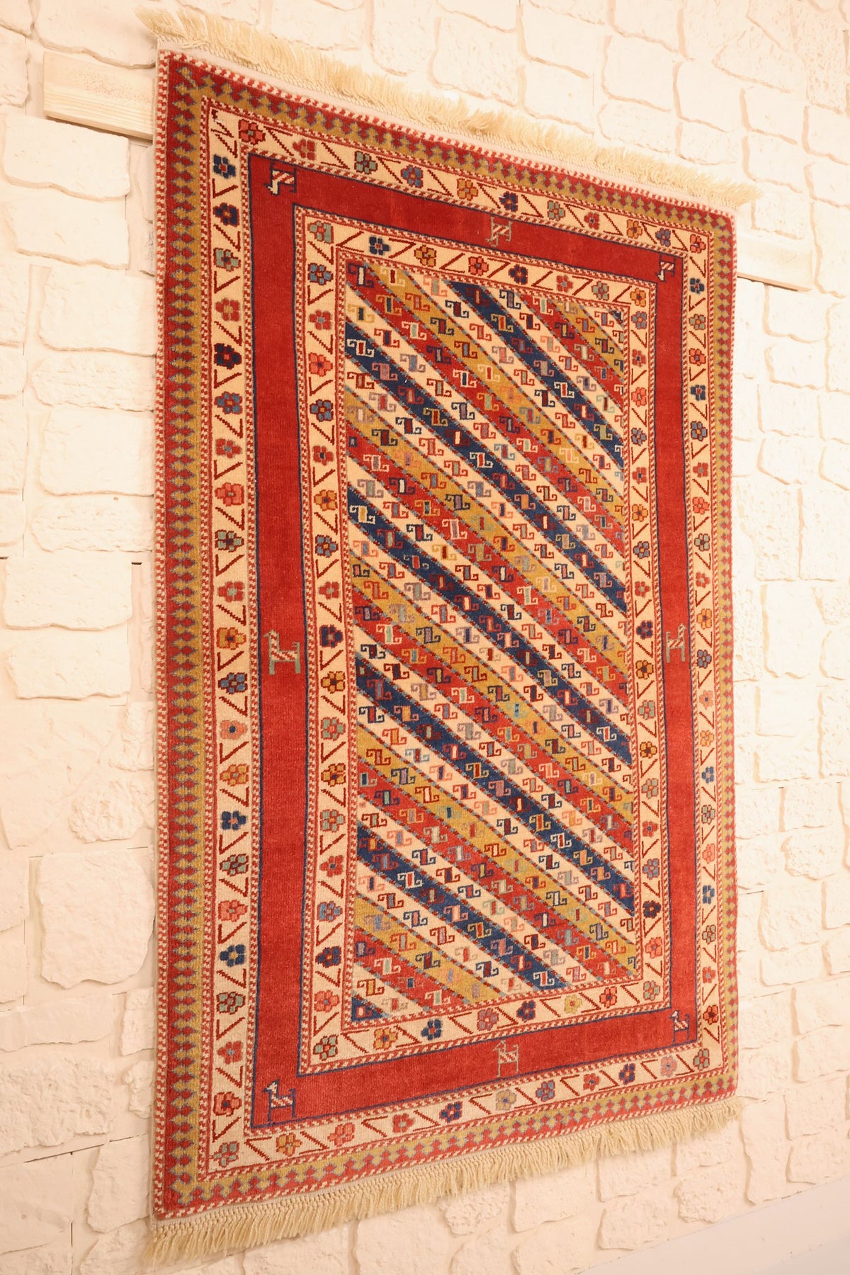 Tapis Safir rectangulaire rouge et ivoire vu de biais, bandes diagonales et franges écrues