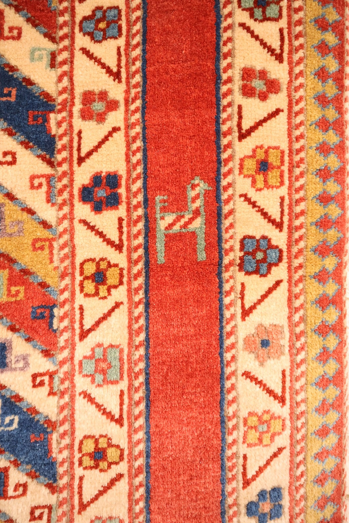 Bordure du tapis Safir : cadre rouge à figure animale et rosettes ivoire