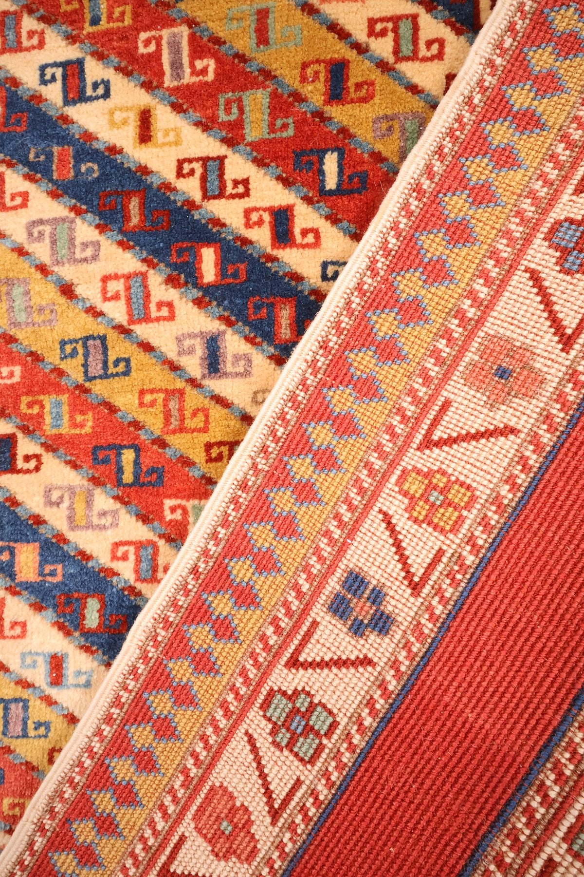 Envers du tapis Safir en laine, nœuds visibles le long de la bordure jaune à losanges