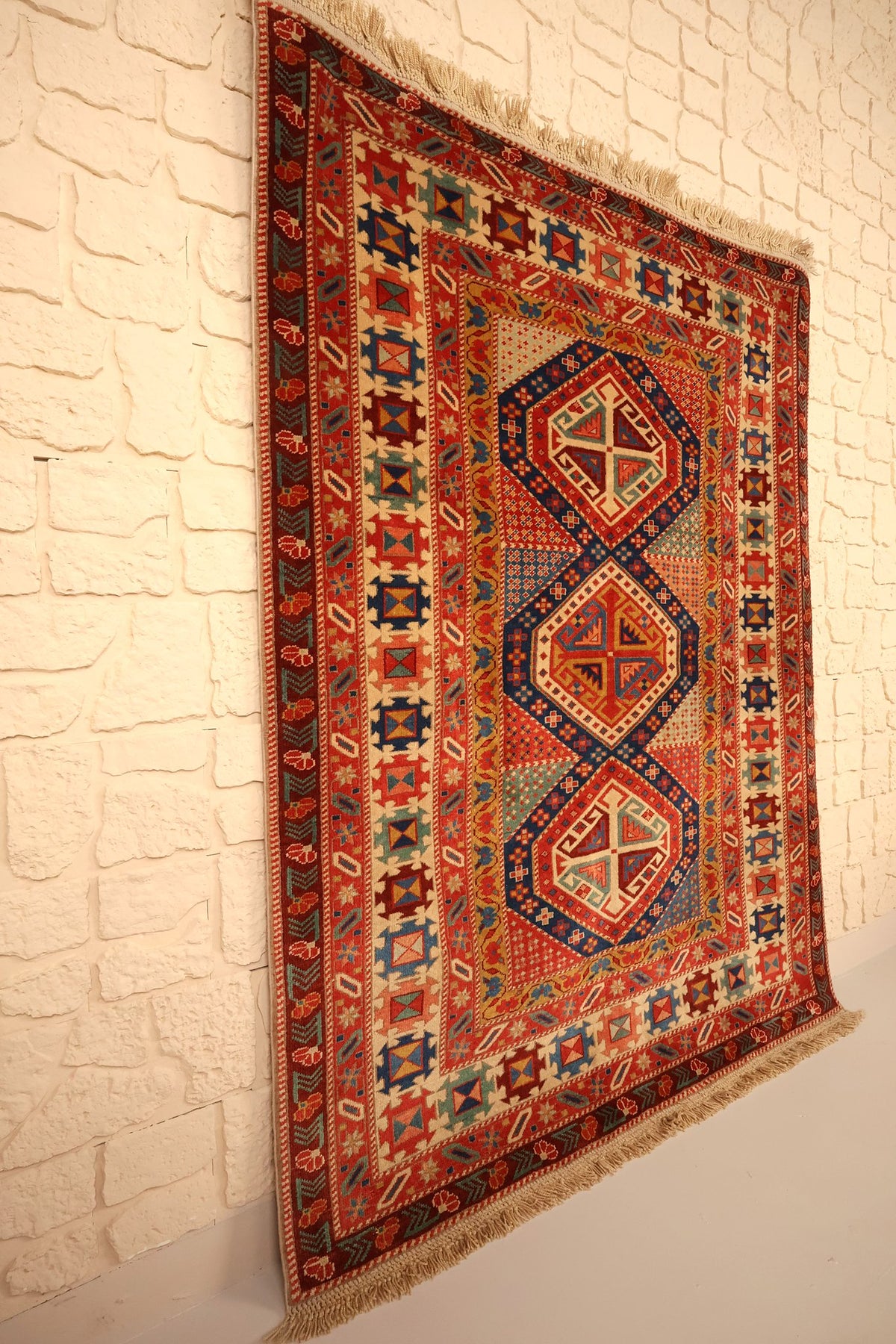 Tapis Safir noué main, vue de biais montrant le champ rouge et ses bordures multiples