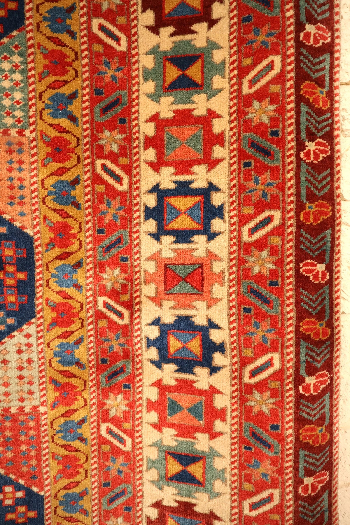Bordures du tapis Safir : carrés étoilés ivoire, rinceaux jaunes et chevrons brun foncé