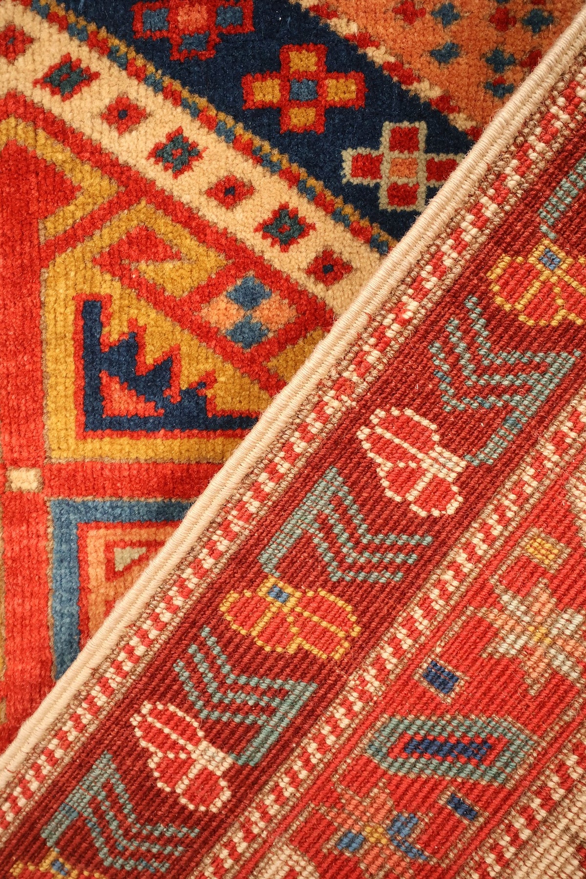 Coin replié du tapis Safir en laine, bordure à chevrons et semis de croix