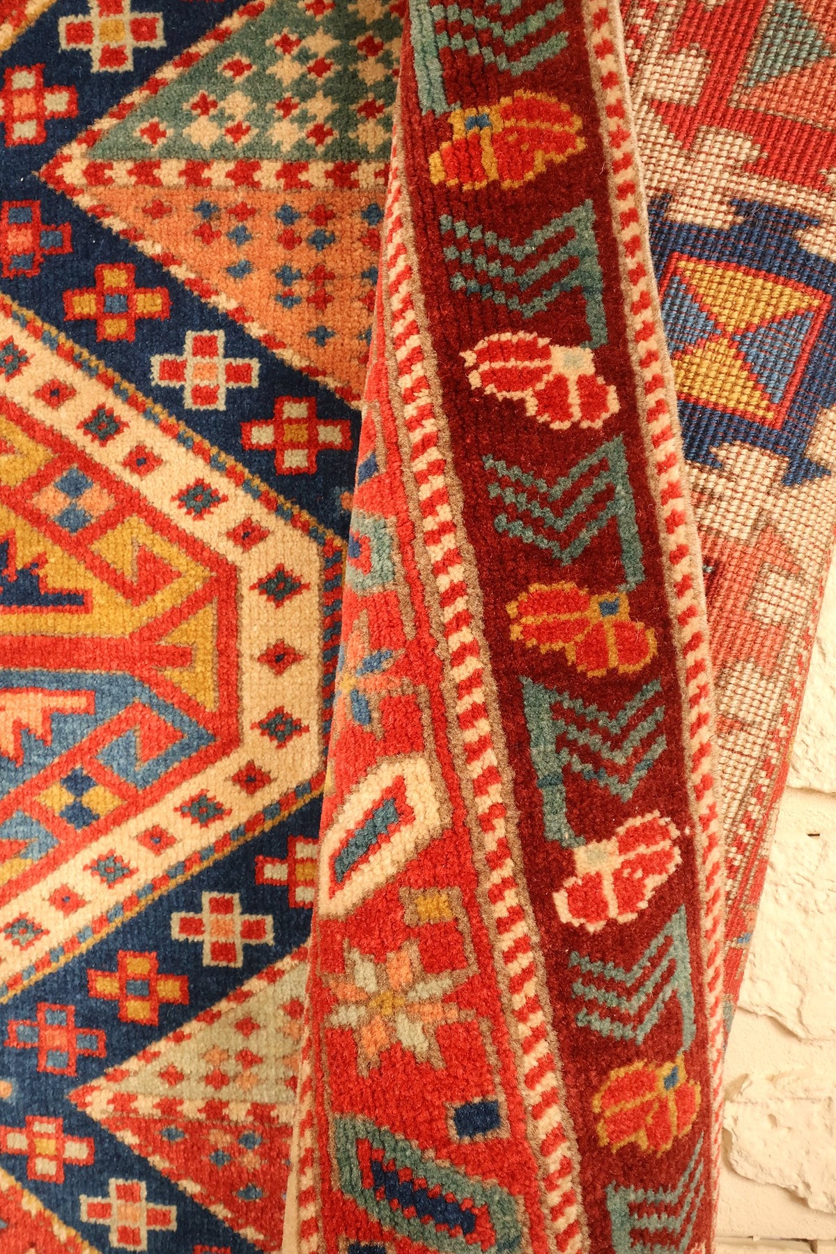 Repli du tapis Safir rouge, écoinçons à semis et bande brune à chevrons bleu-vert