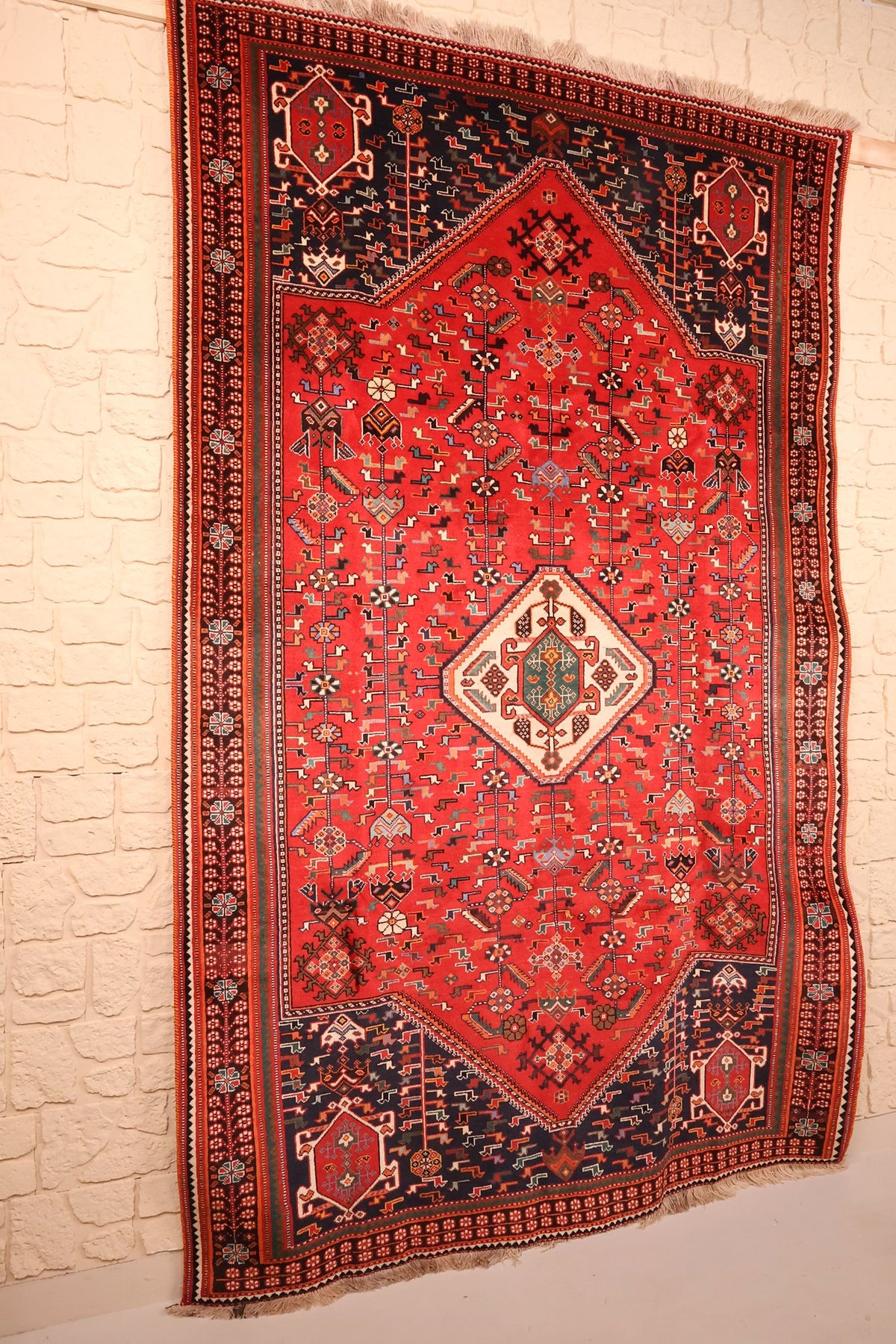 Tapis Shiraz en laine vu de biais, écoinçons bleu nuit et bordure brune