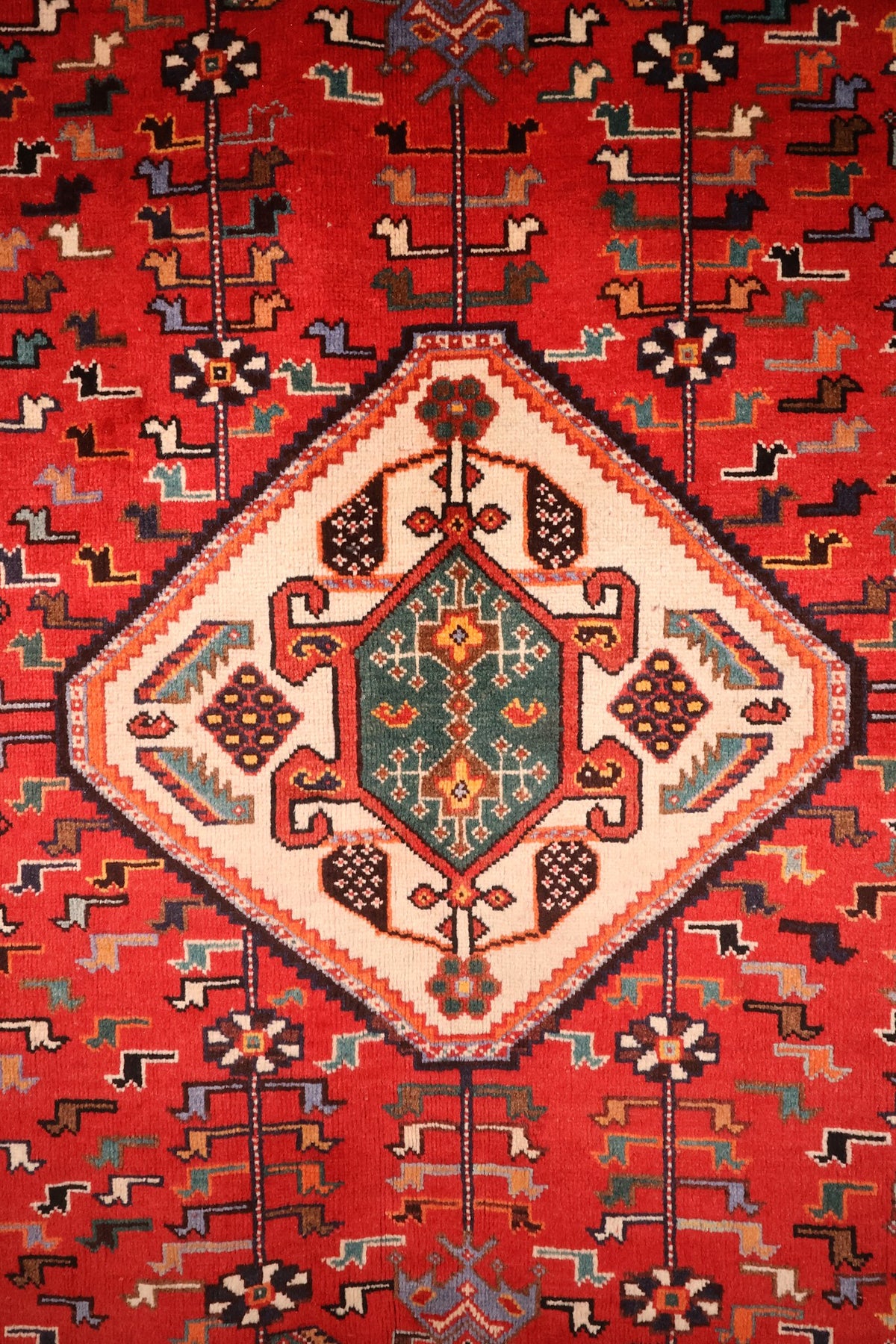Détail du médaillon losangé ivoire à cœur vert du tapis Shiraz rouge