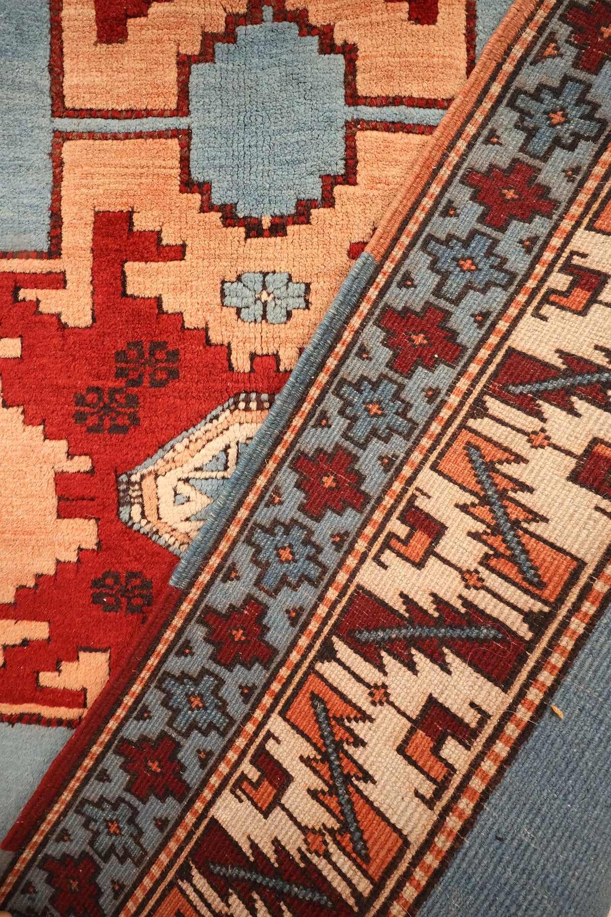 Coin replié du tapis Shirvan bleu et rouge, bordures et cartouche octogonal ivoire