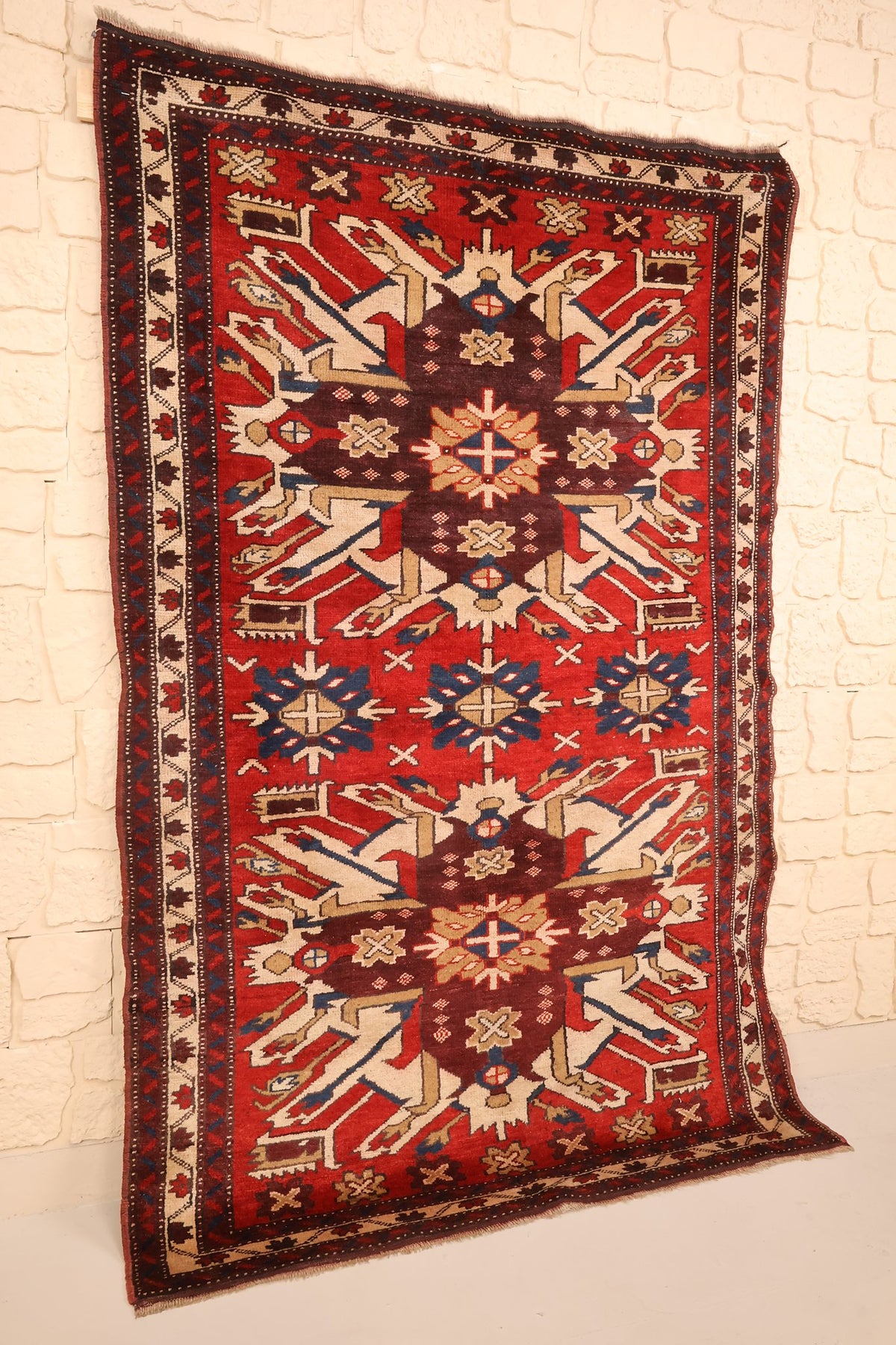 Tapis Shirvan en laine noué main, vue de biais montrant le champ rouge et la bordure ivoire