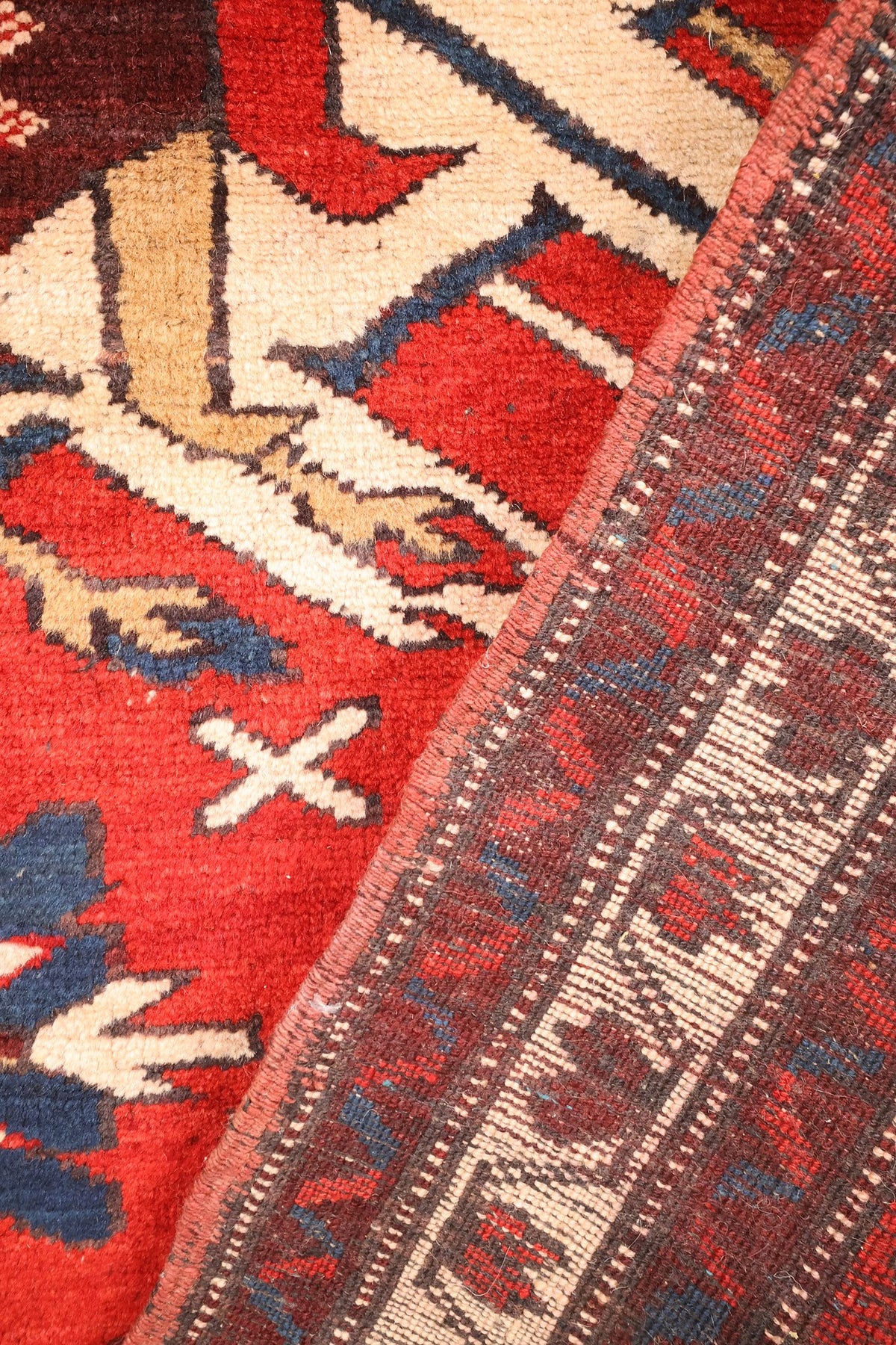 Coin replié du tapis Shirvan rouge, contre-bordures sombres à galons dentelés