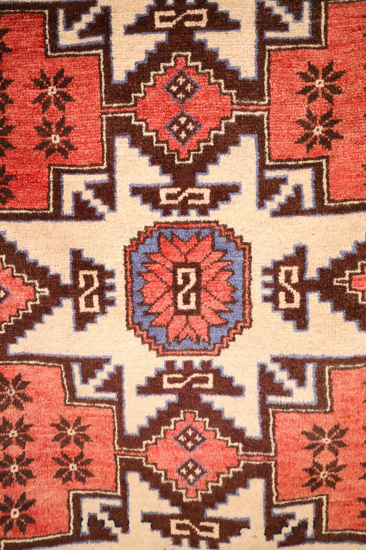 Détail d'un médaillon étoilé ivoire et de son cartouche bleu à rosette rouge, tapis Shirvan