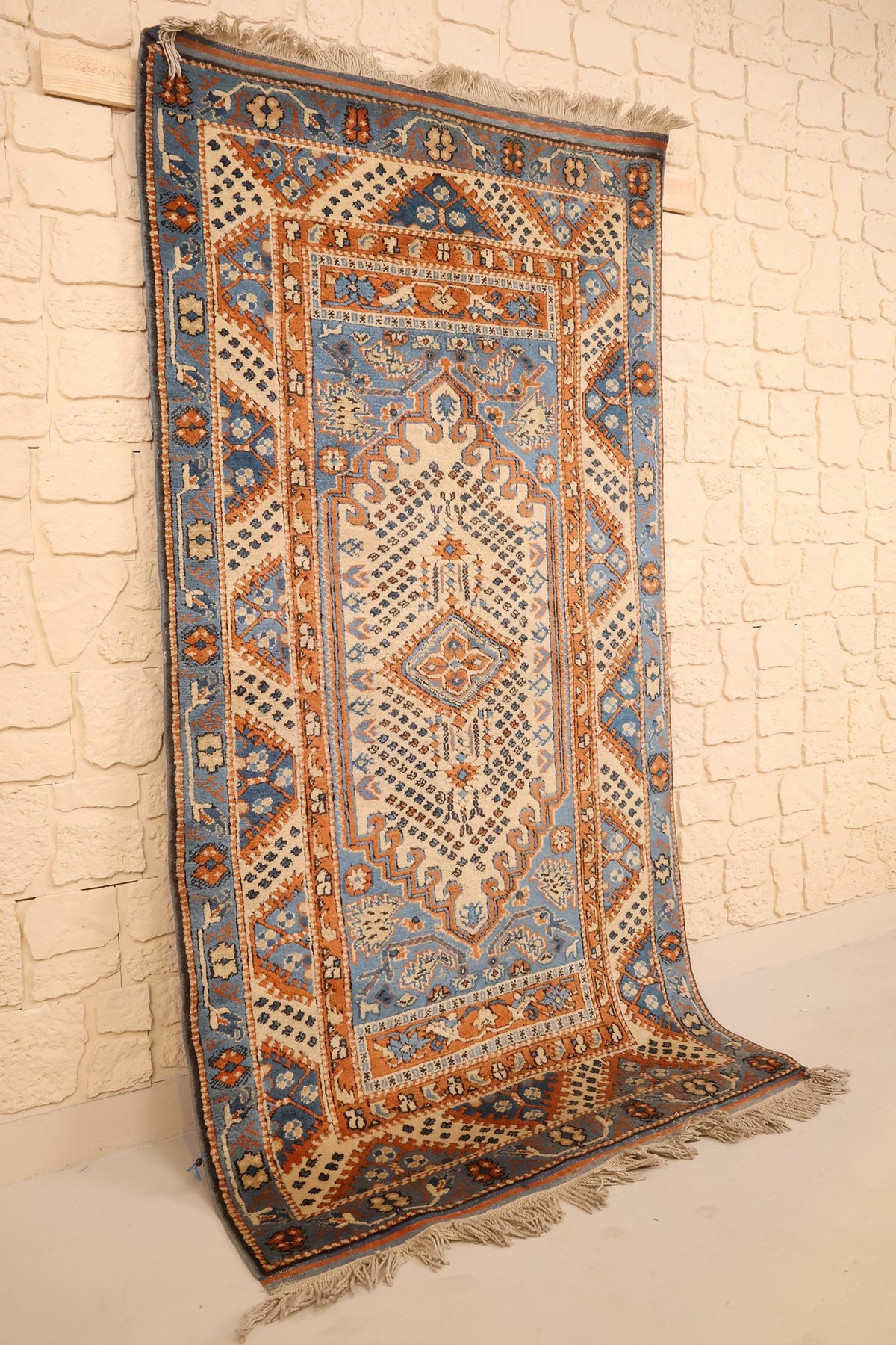 Tapis Shirvan en laine nouée à la main, vue de biais montrant le champ beige