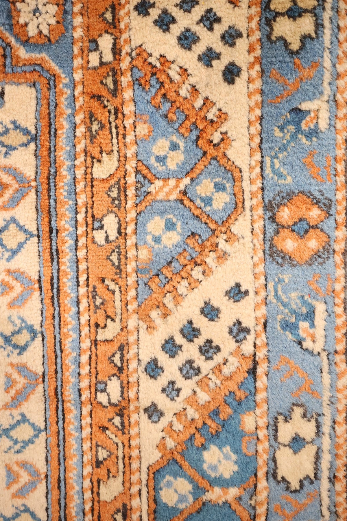 Bordures bleues à losanges et rosettes du tapis Shirvan, cadre orange denté