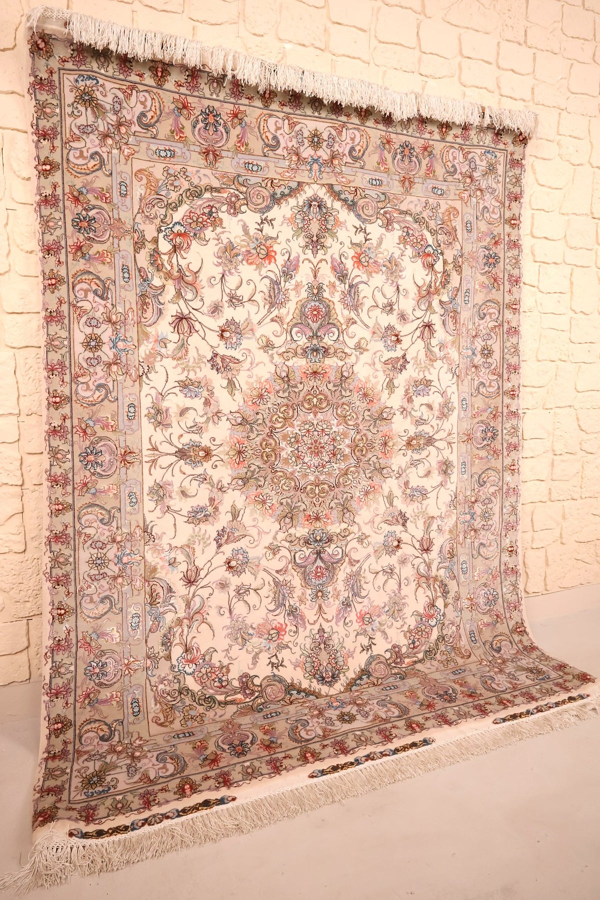 Tapis Tabriz beige et rose vu de biais, champ fleuri et franges blanches