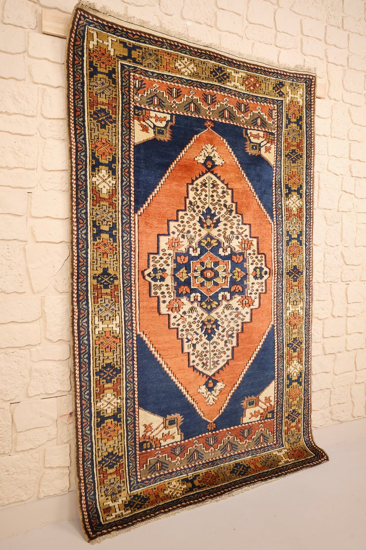 Tapis Tachpinar rectangulaire orange, vue de biais contre un mur clair