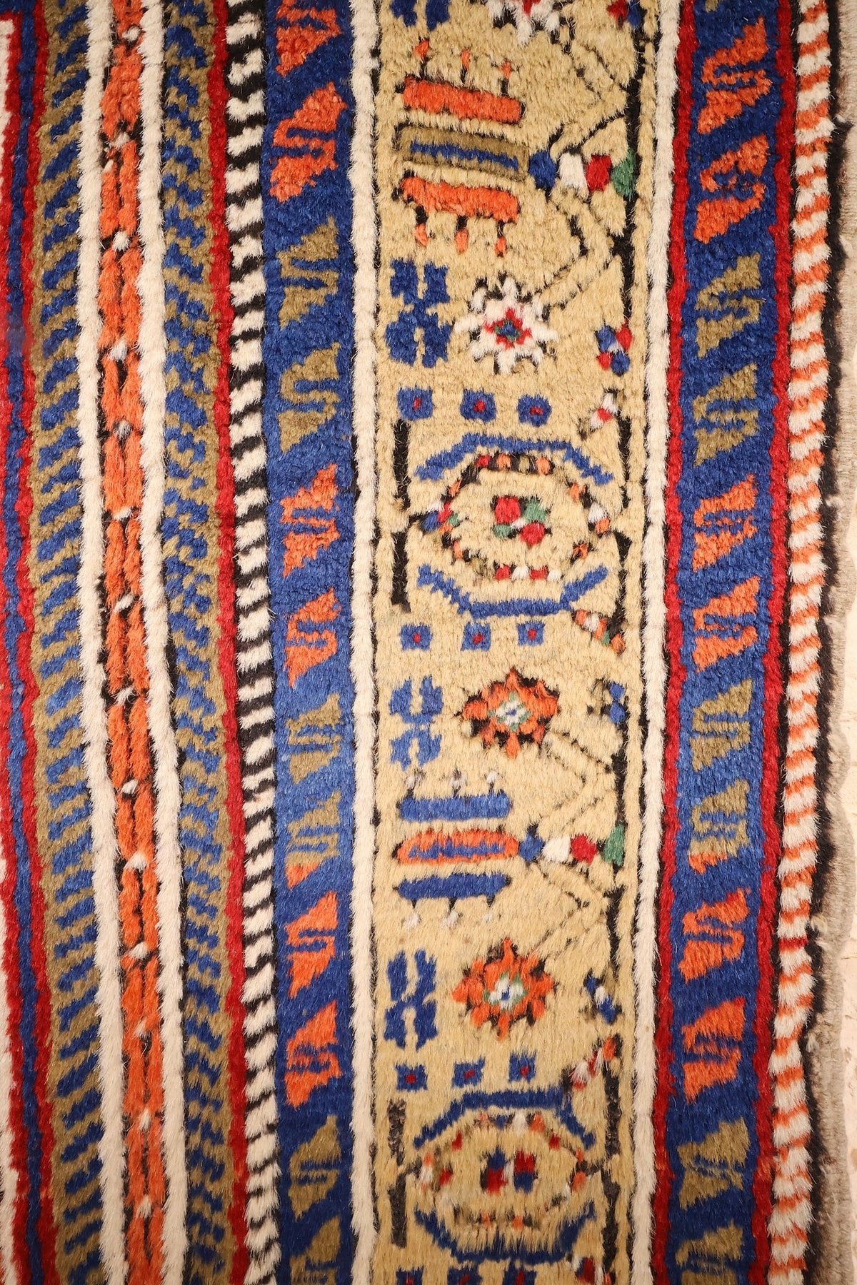 Bordure beige à rosettes et galons bleus, blancs et rouges du tapis Tachpinar