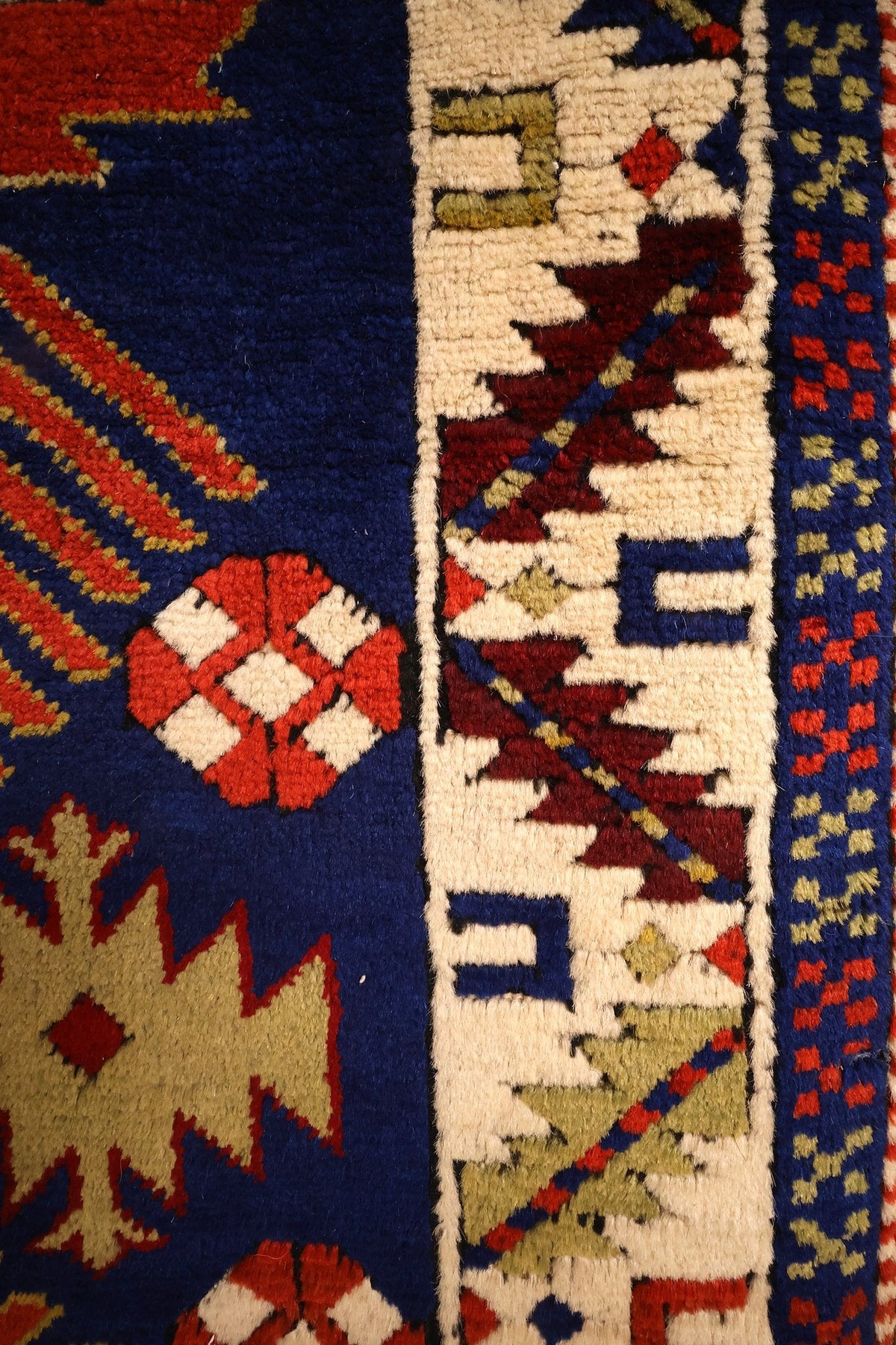 Détail de la bordure ivoire à crochets rouges et bleus, rosette blanche sur champ bleu nuit