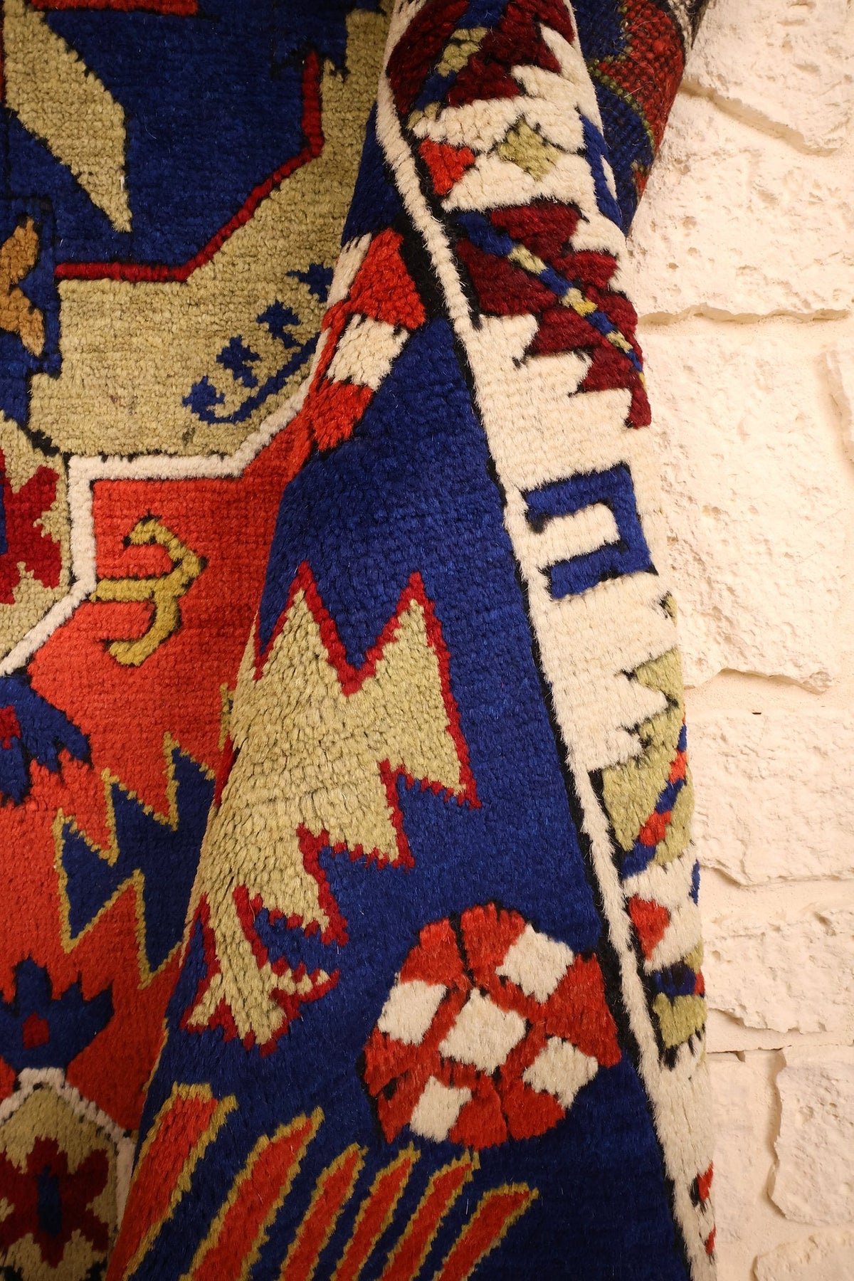 Coin replié du tapis Tachpinar bleu et rouge, étoiles dentelées vertes près de la bordure
