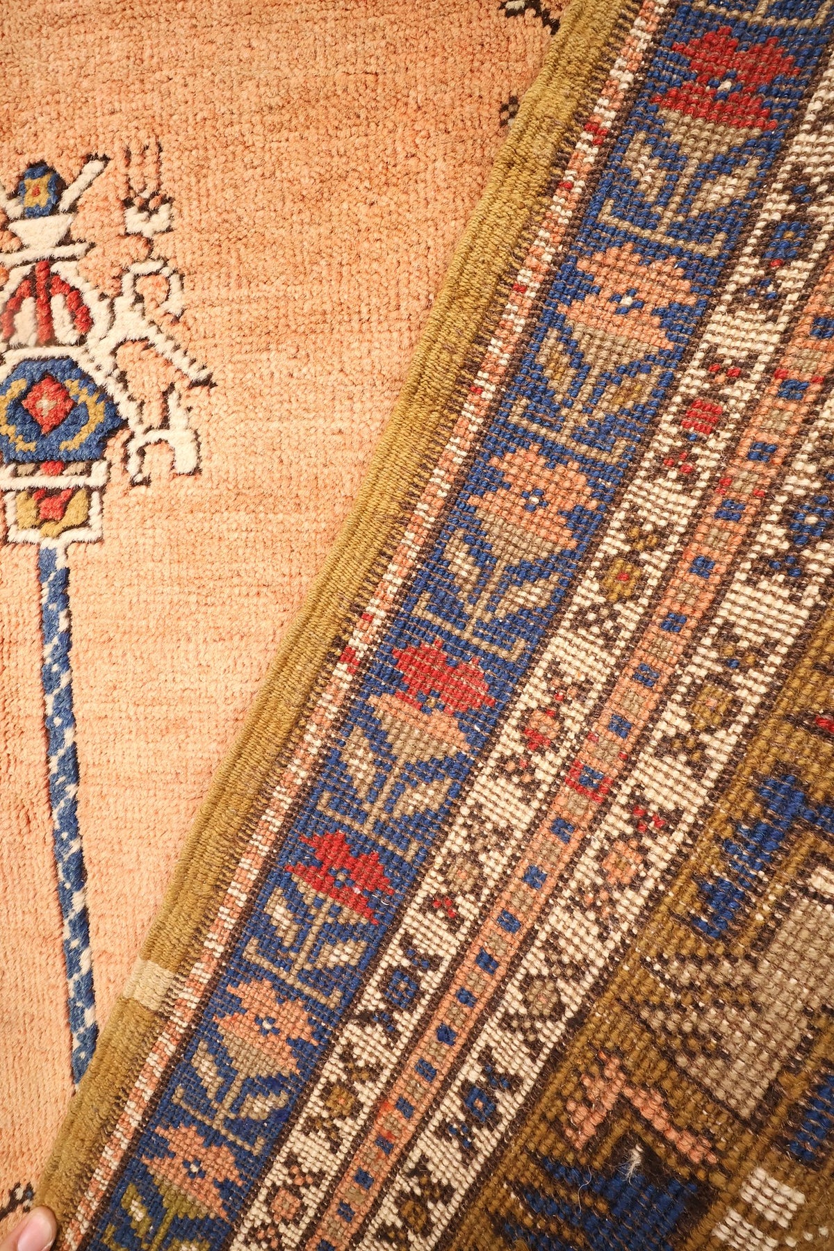 Coin replié du tapis Tachpinar, bordure bleue à fleurs roses et rouges