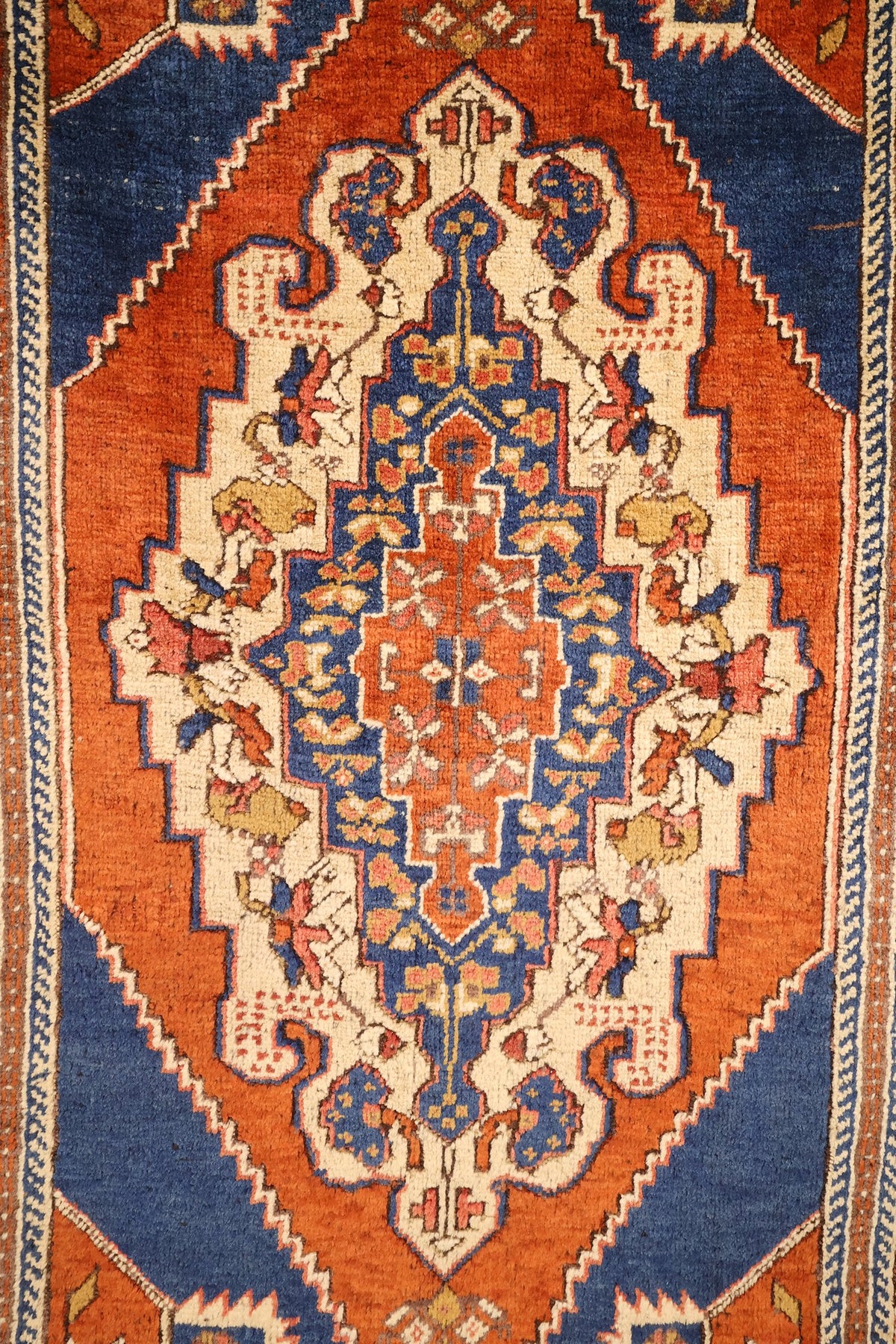 Détail du médaillon crénelé ivoire et bleu du tapis Tachpinar orange