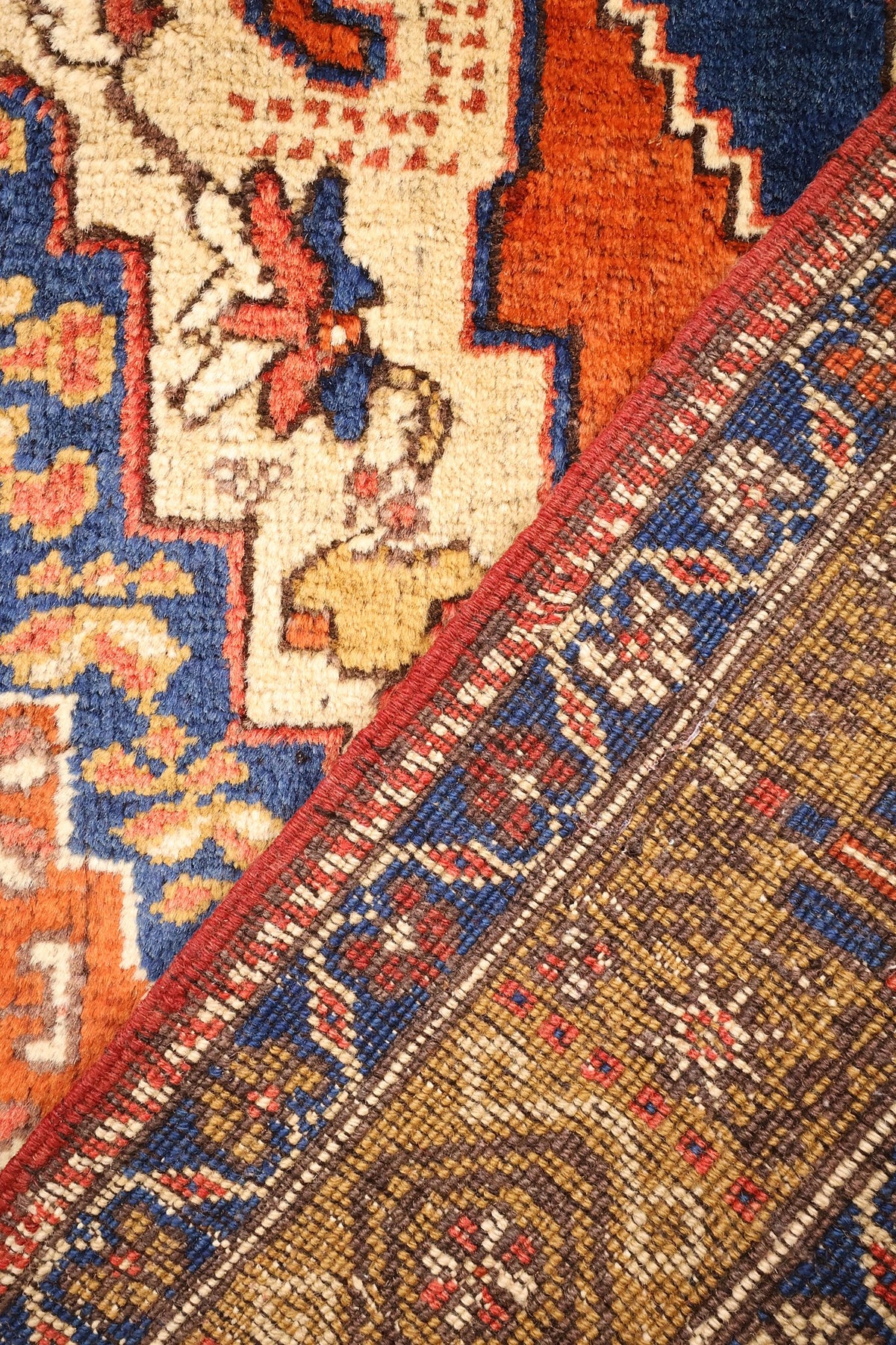 Coin replié du tapis Tachpinar, envers et nœuds visibles près des écoinçons bleus