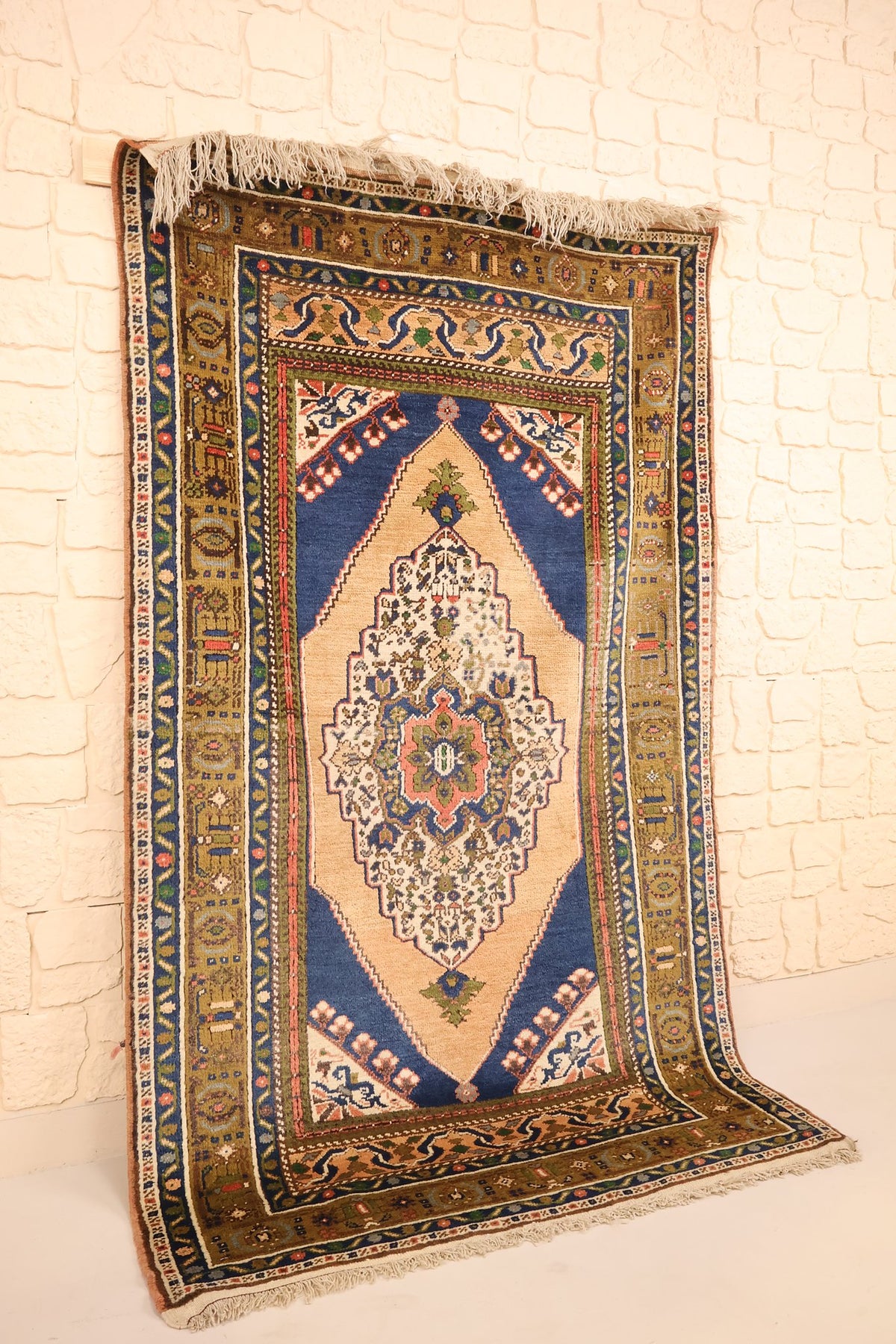 Vue de biais du tapis Tachpinar rectangulaire bleu, beige et marron à médaillon central