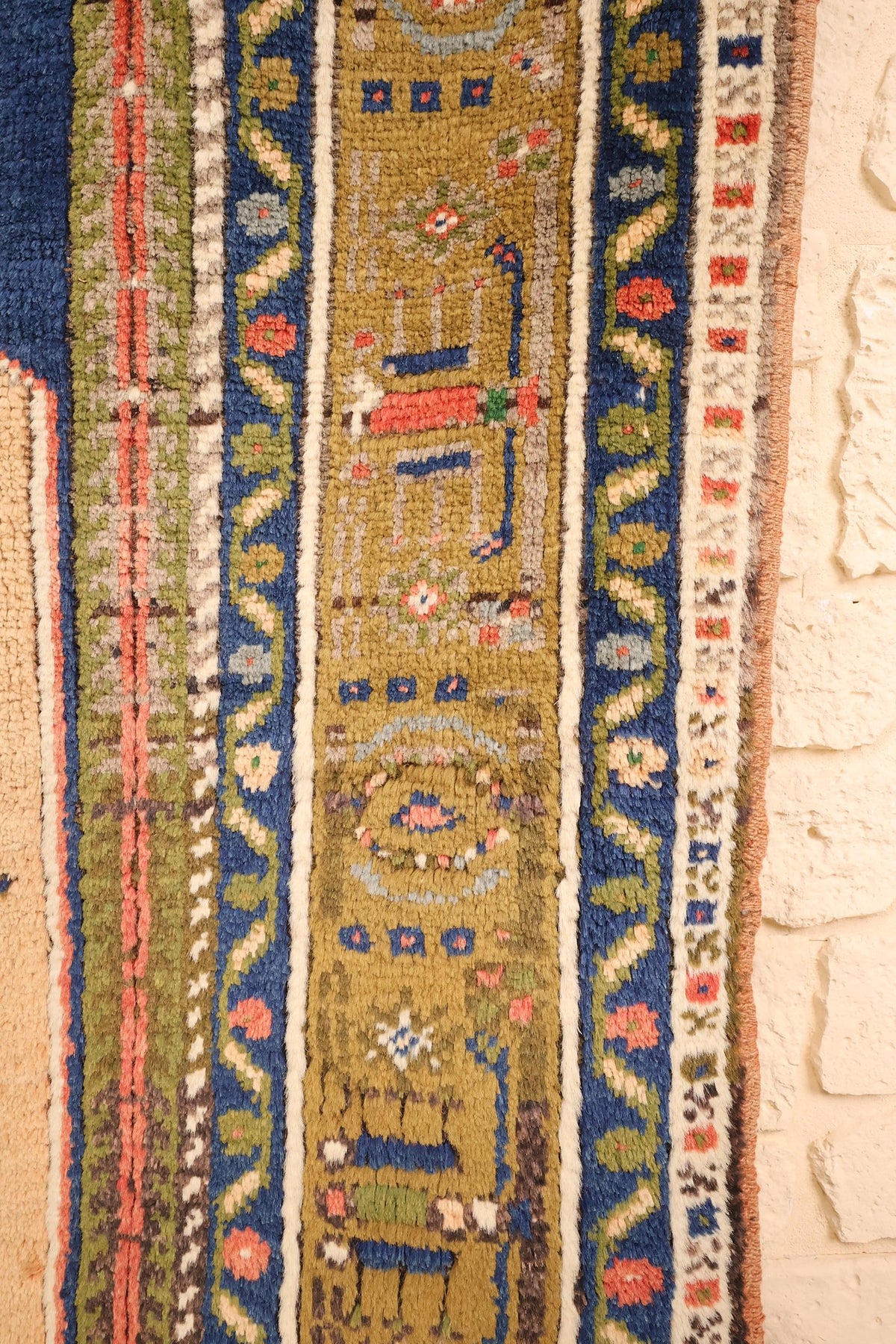 Bordure jaune-olive à cartouches fleuris et bandes bleues à rinceaux du tapis Tachpinar bleu