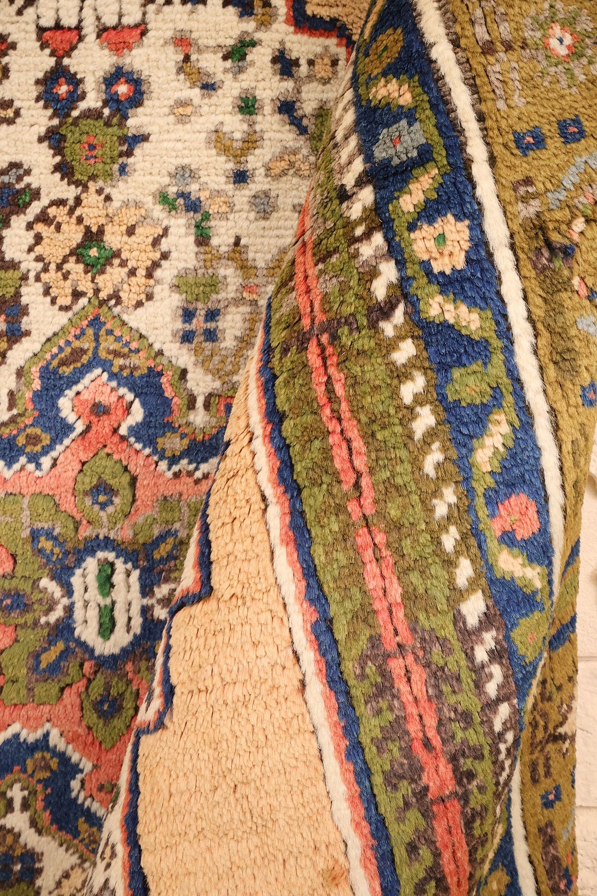 Coin replié du tapis, écoinçon ivoire et bandes florales bleu et vert