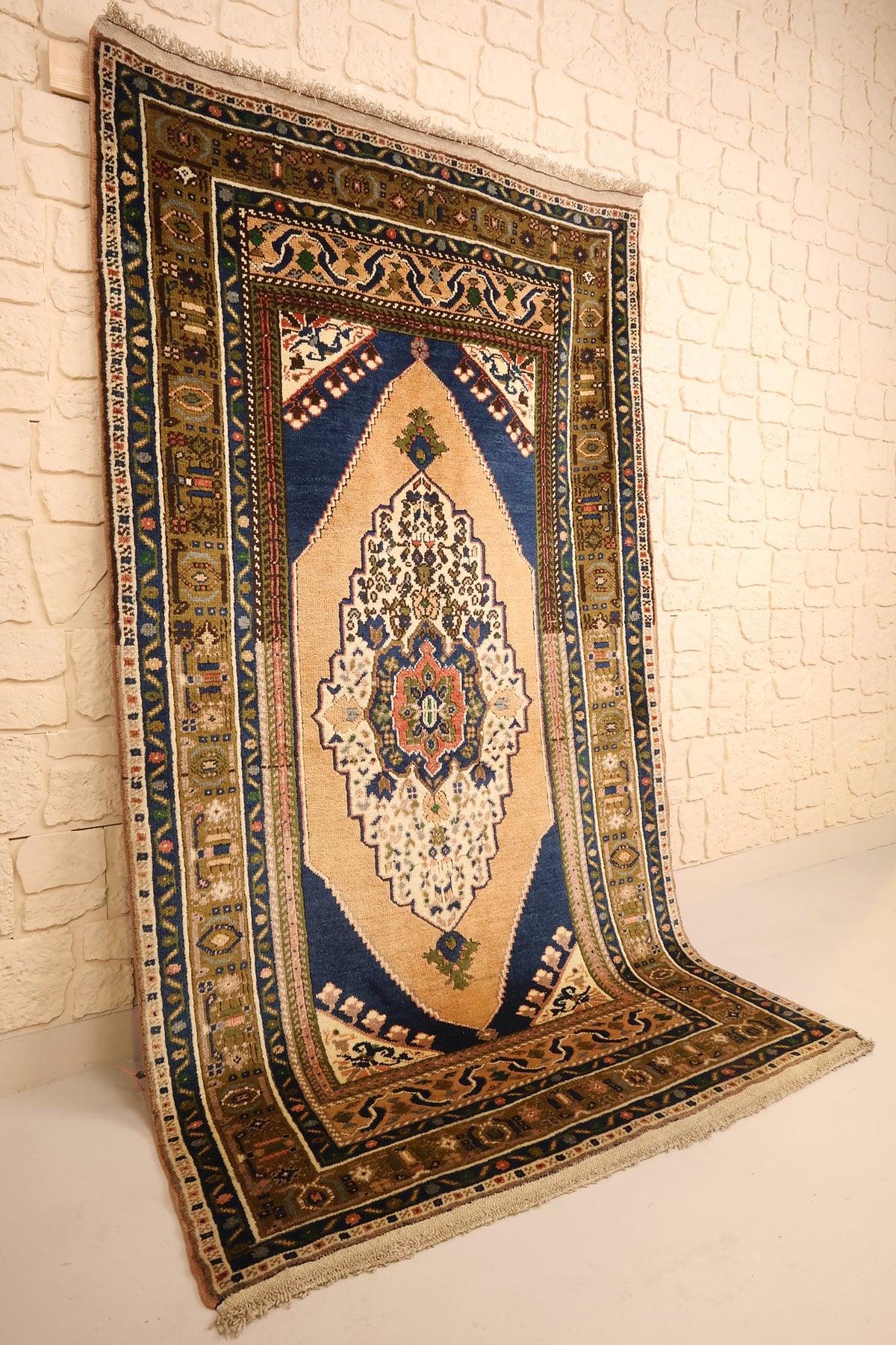 Tapis Tachpinar beige rectangulaire vu de biais, large cadre bleu nuit et bordures ocre