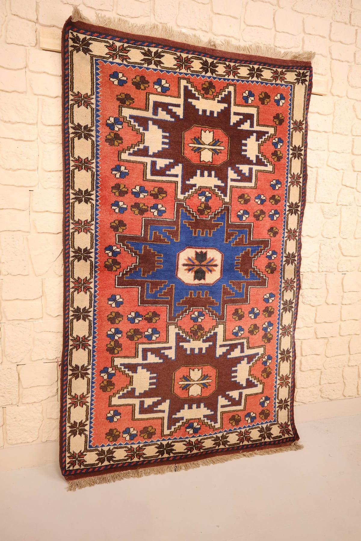 Tapis Yagci Bedir orange et bleu vu de biais, bordure ivoire à palmettes sombres