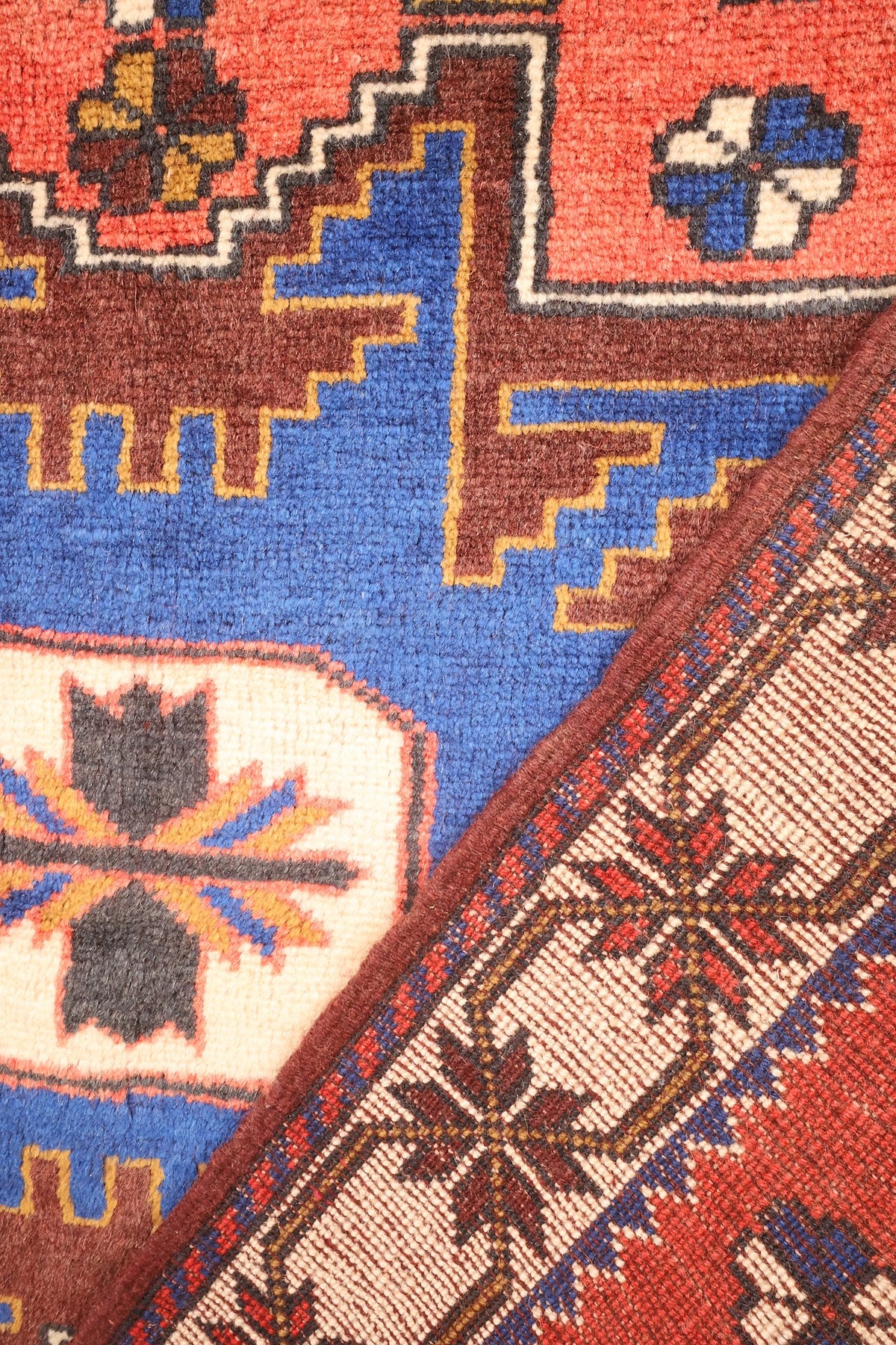Coin replié du tapis Yagci Bedir envers et nœuds visibles sous le motif bleu