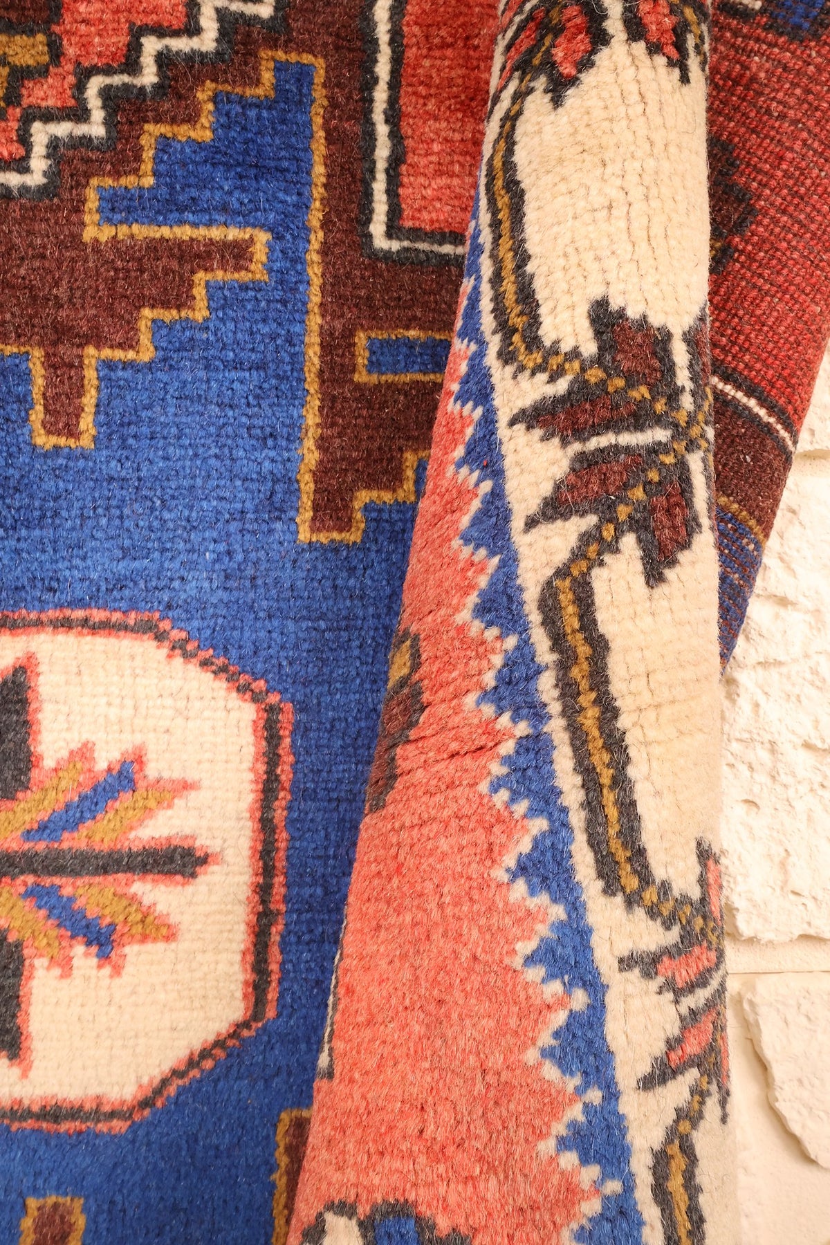 Pli du tapis Yagci Bedir montrant l'octogone ivoire et la bordure à feuilles brunes