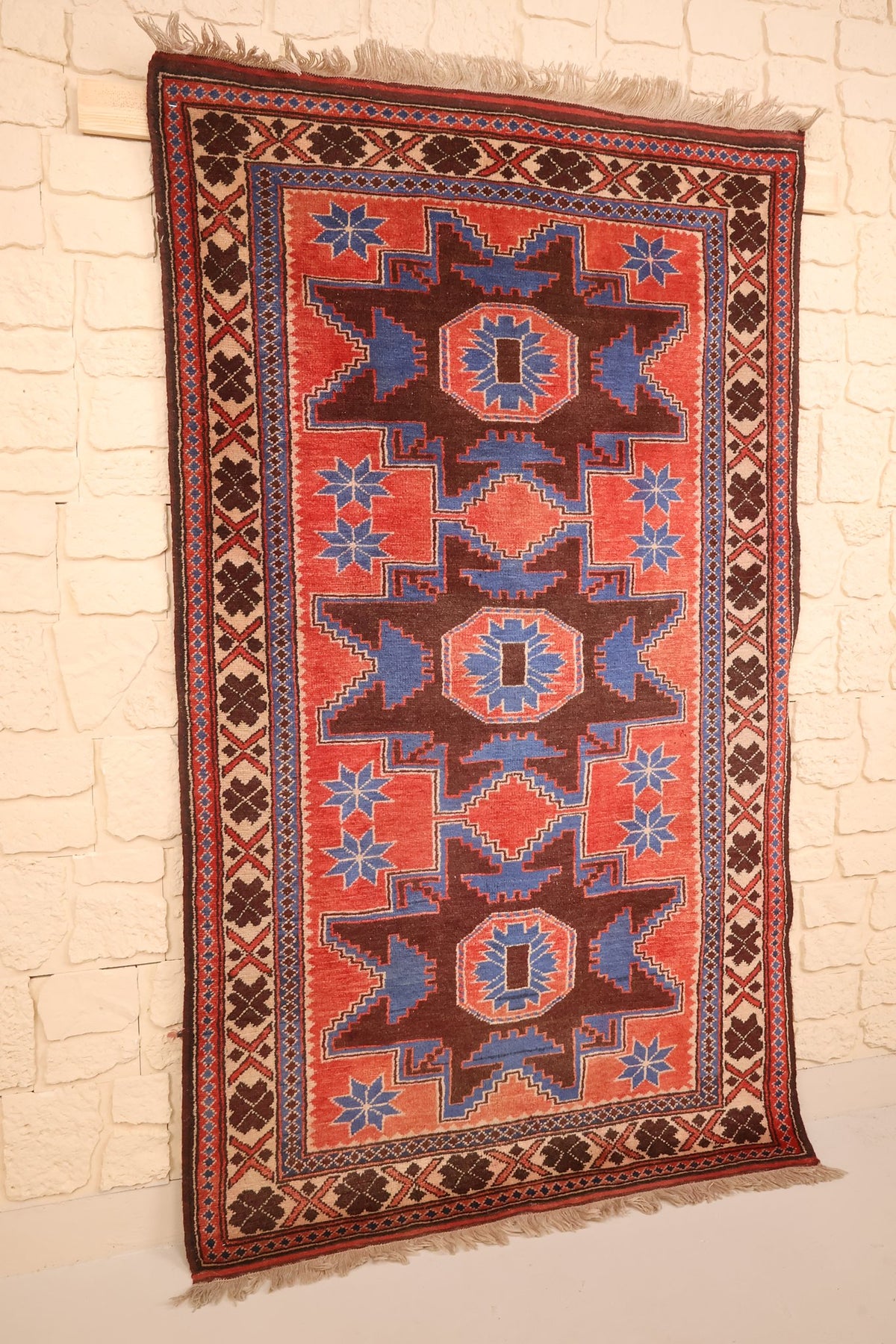 Vue de biais du tapis Yagci Bedir rectangulaire rouge, franges écrues aux deux extrémités