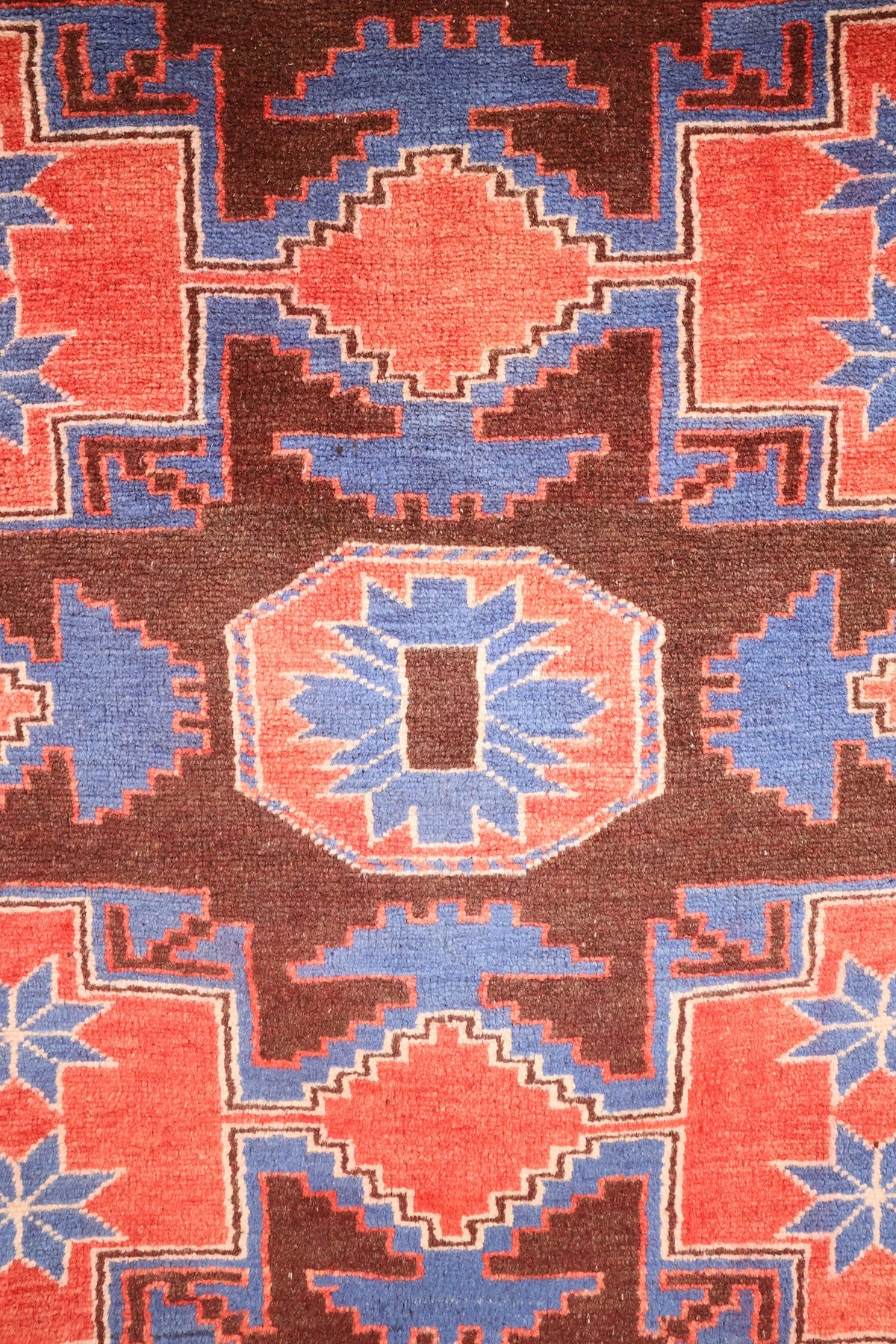 Détail d'un médaillon brun centré d'un octogone rouge clair à rayons bleus