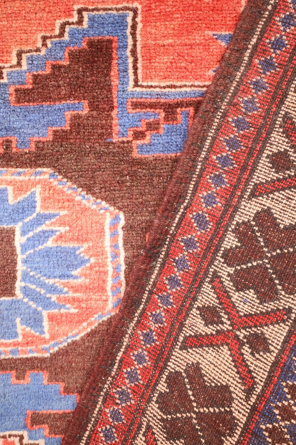 Coin replié du tapis Yagci Bedir rouge, passage du champ aux bordures