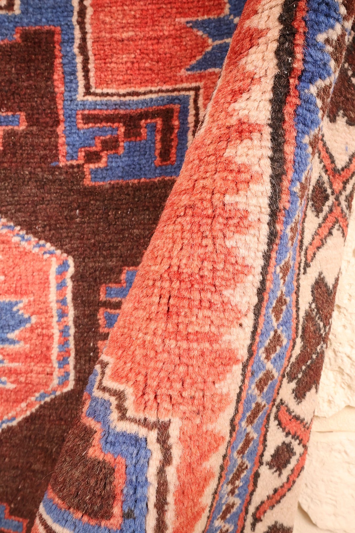 Coin relevé montrant l'épaisseur et les crochets en escalier bleus sur fond rouge