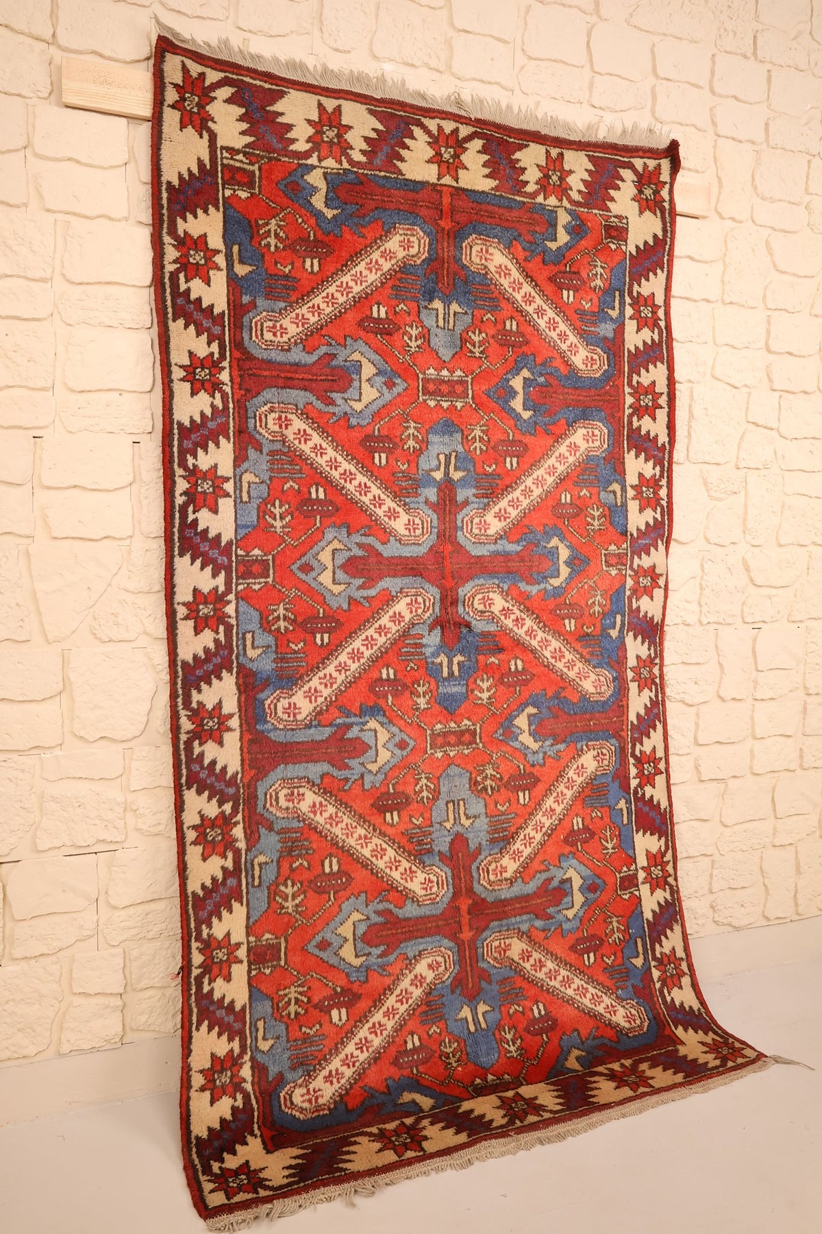 Vue de biais du tapis Yagci Bedir rouge à grands motifs anguleux en croix et franges claires