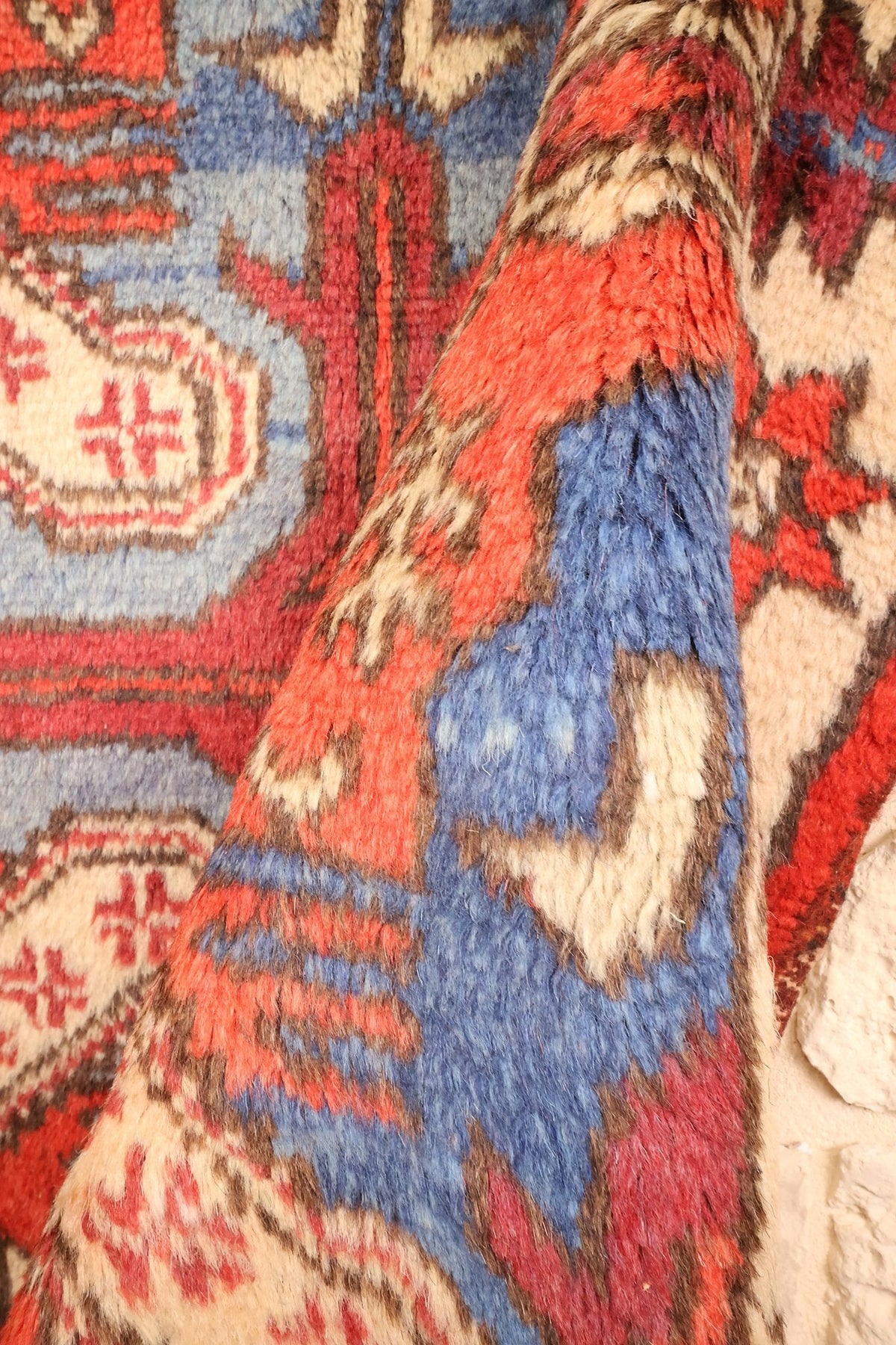 Coin replié du tapis rouge et bleu, épaisseur du tissage visible