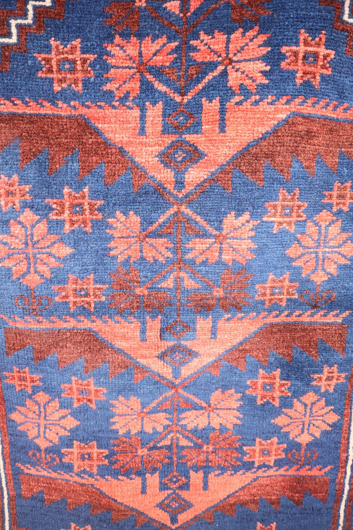 Détail du champ bleu du tapis Yagci Bedir : rosettes étoilées et motifs végétaux anguleux roses