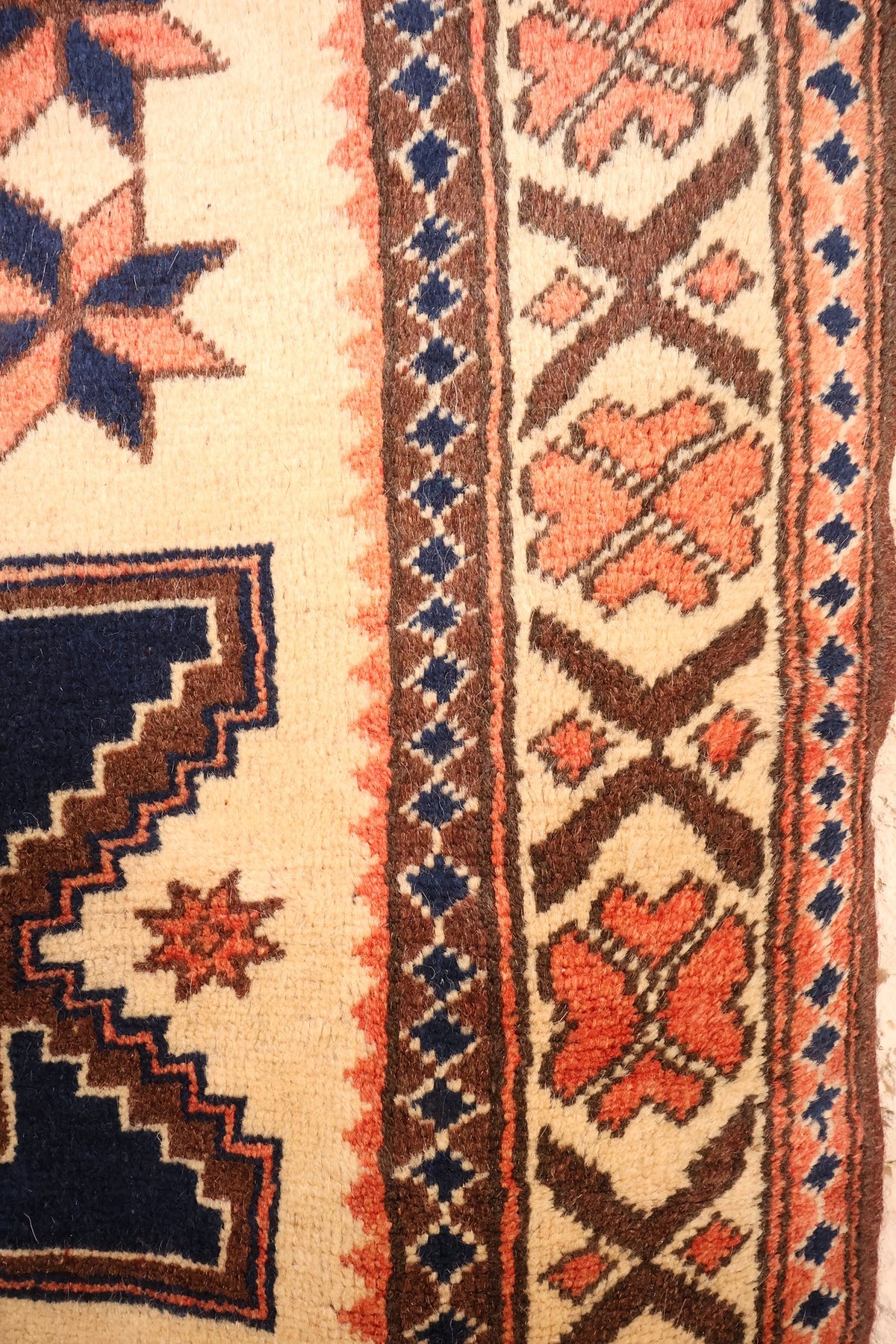 Bordure ivoire à rosettes orange et filets de losanges bleus du tapis Yagci Bedir