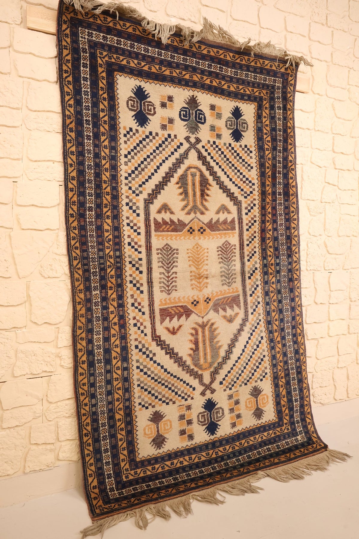 Tapis Yagci Bedir beige, bleu et orange vu de biais, médaillon en losange crénelé
