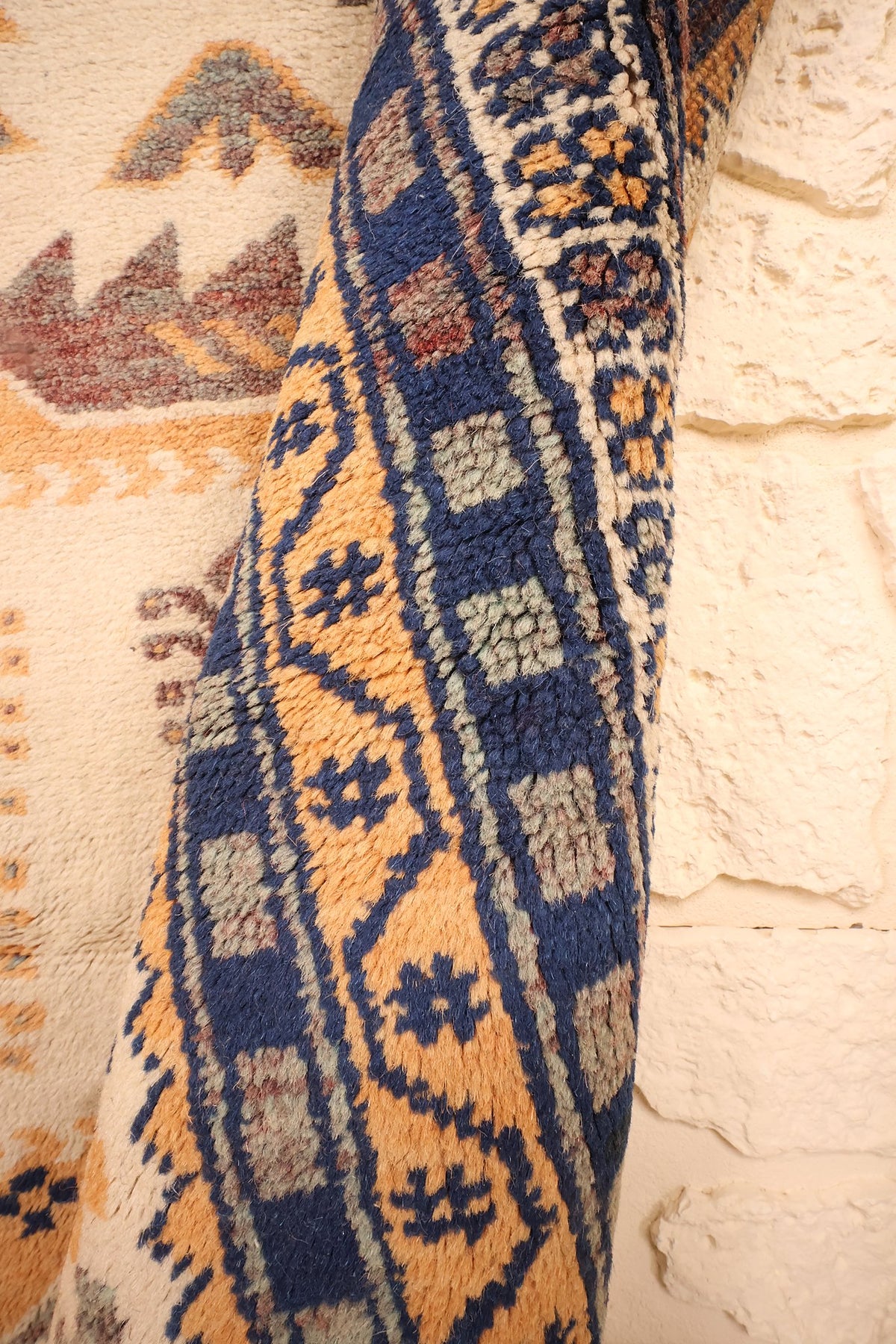 Pli du tapis Yagci Bedir montrant la bande orange à motifs bleus en relief