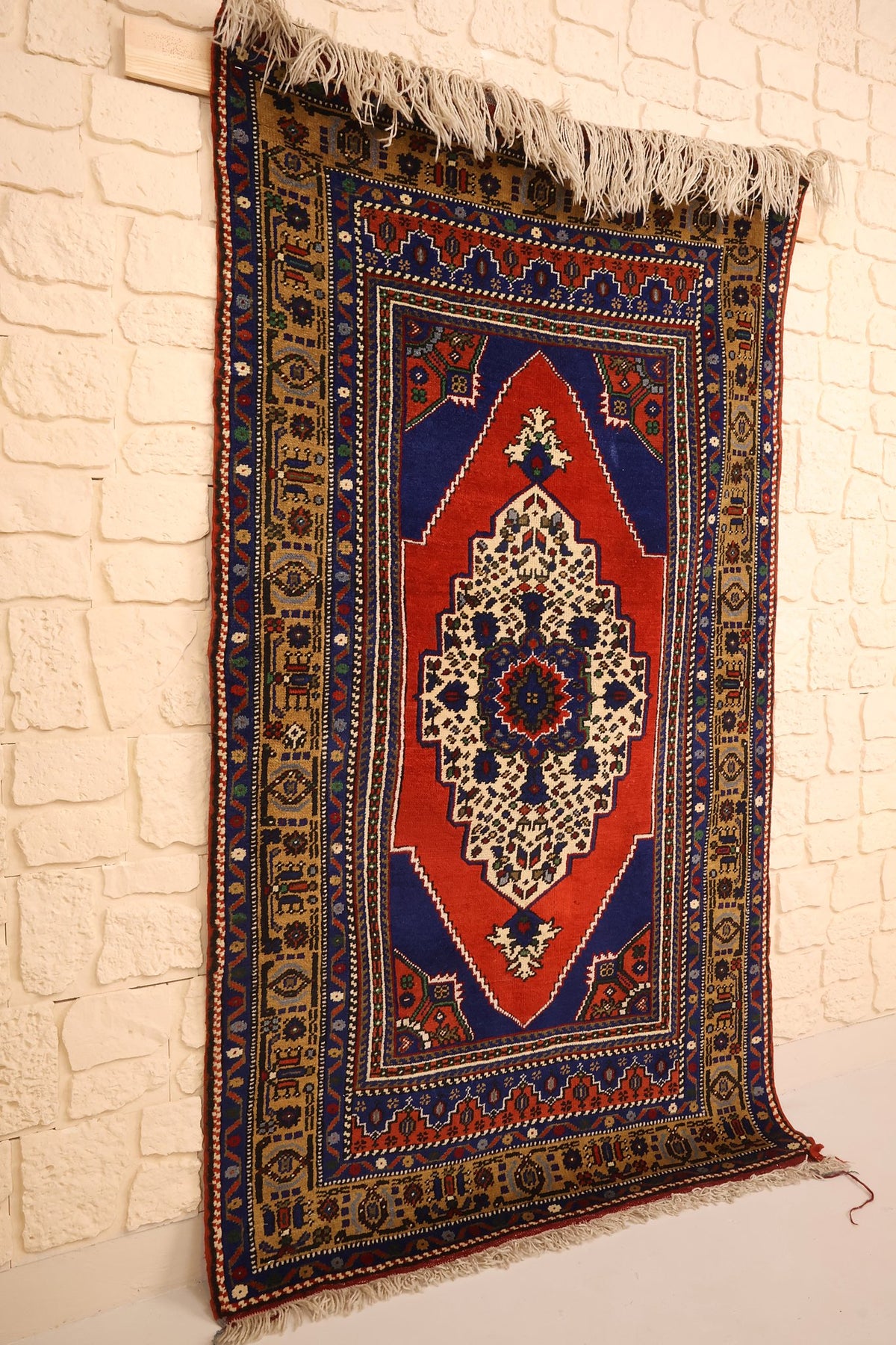 Tapis Yahyali rectangulaire rouge et bleu vu de biais, franges blanches aux deux bouts