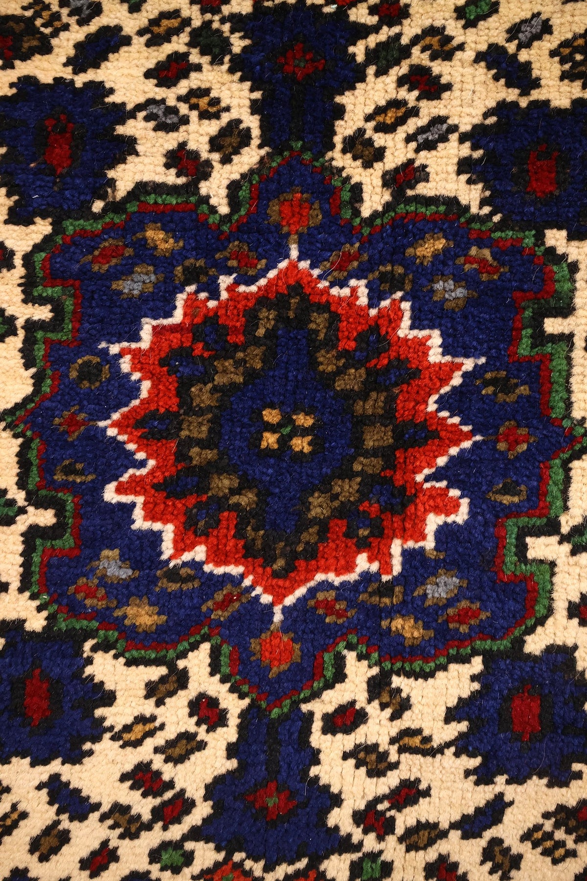 Détail de la rosace centrale rouge et bleue du tapis Yahyali à fond ivoire