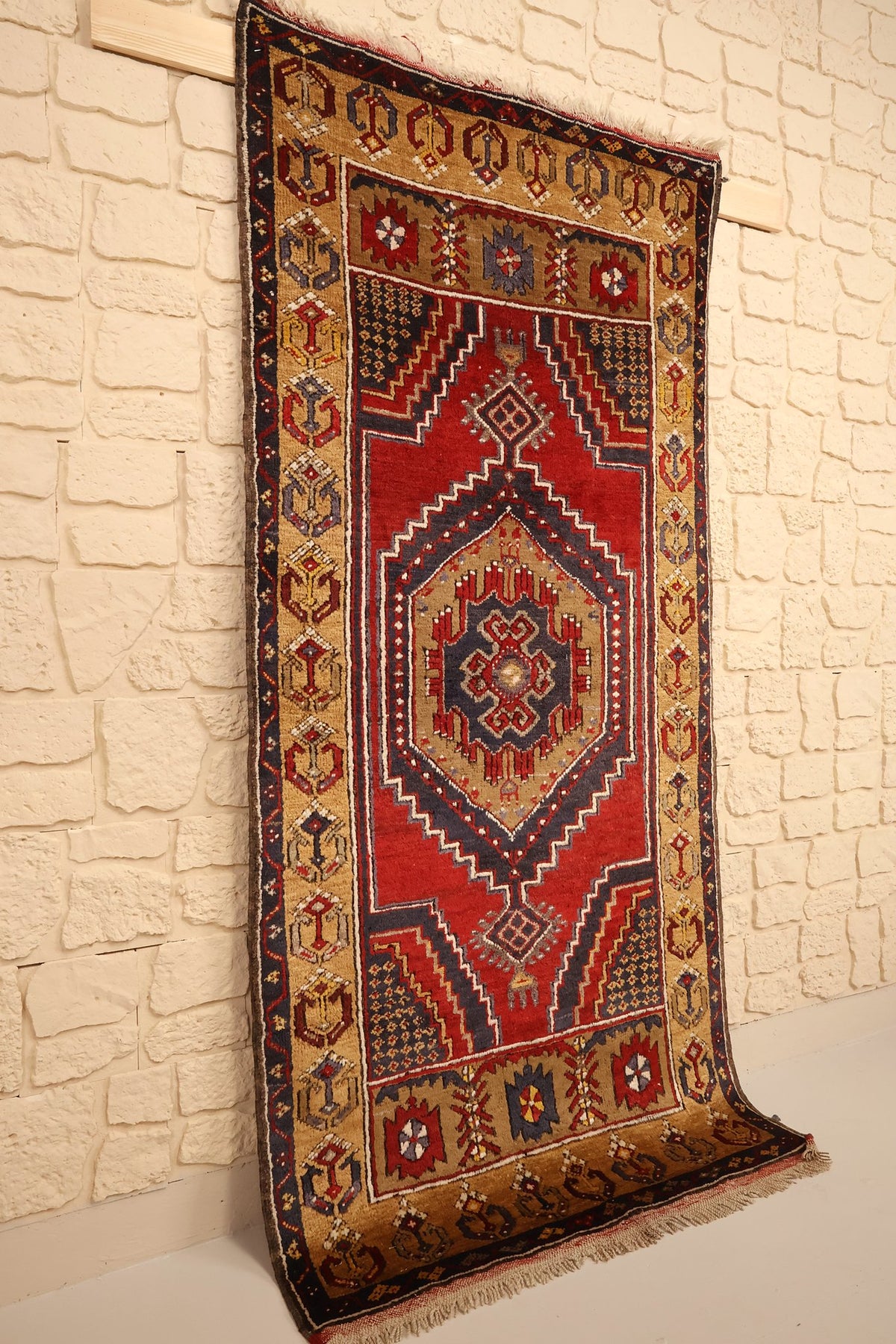 Tapis Yahyali en laine noué main, vue de biais montrant le champ rouge et sa bordure dorée