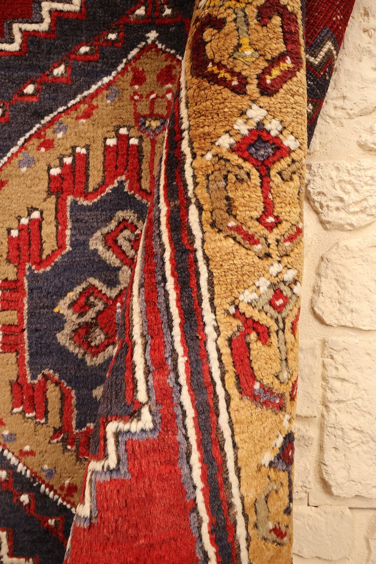 Tapis Yahyali rouge et bleu, pli du bord laissant voir écoinçons et bordure