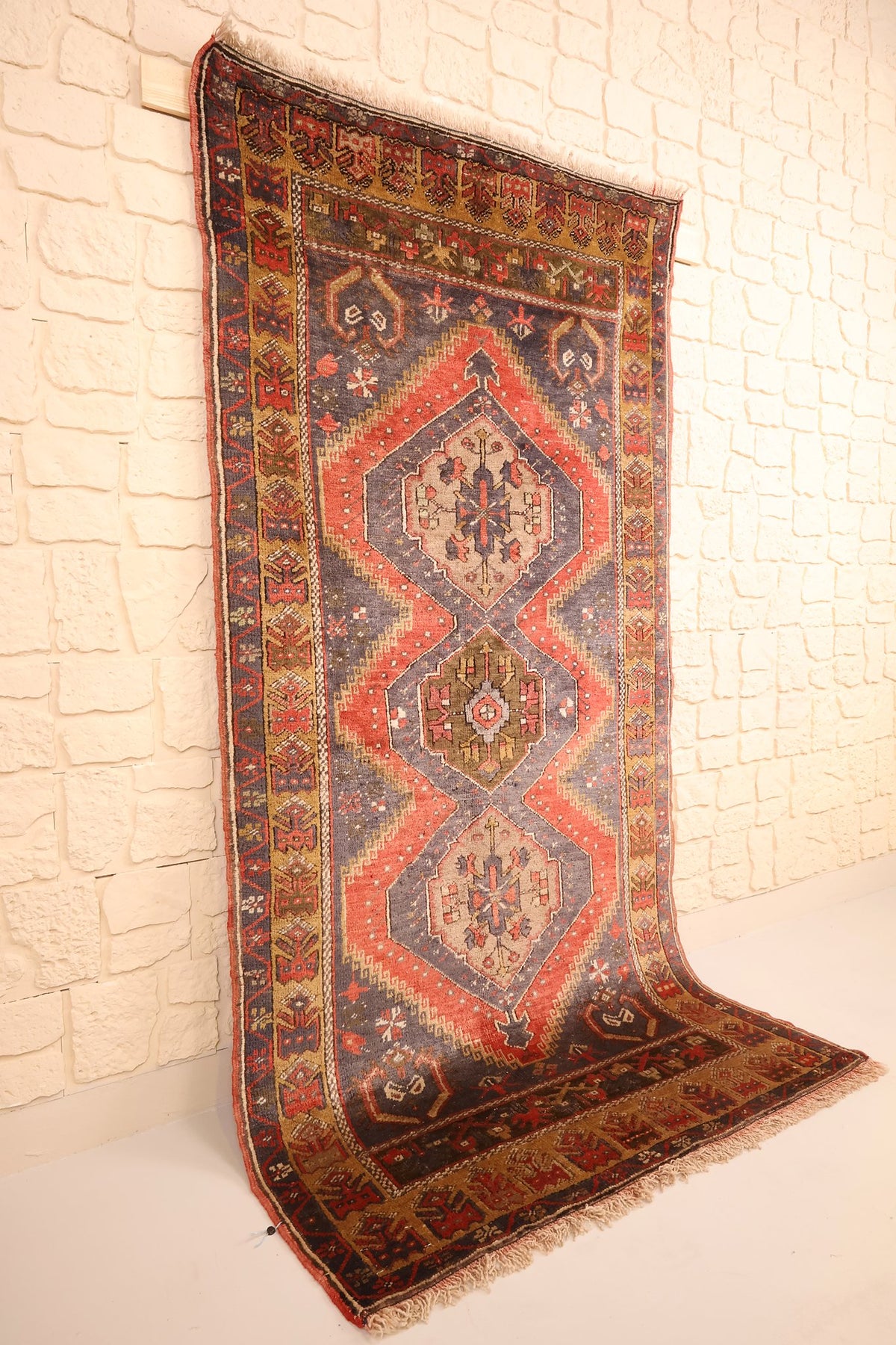 Tapis Yahyali rouge et bleu vu de biais, champ allongé et bordure jaune-ocre