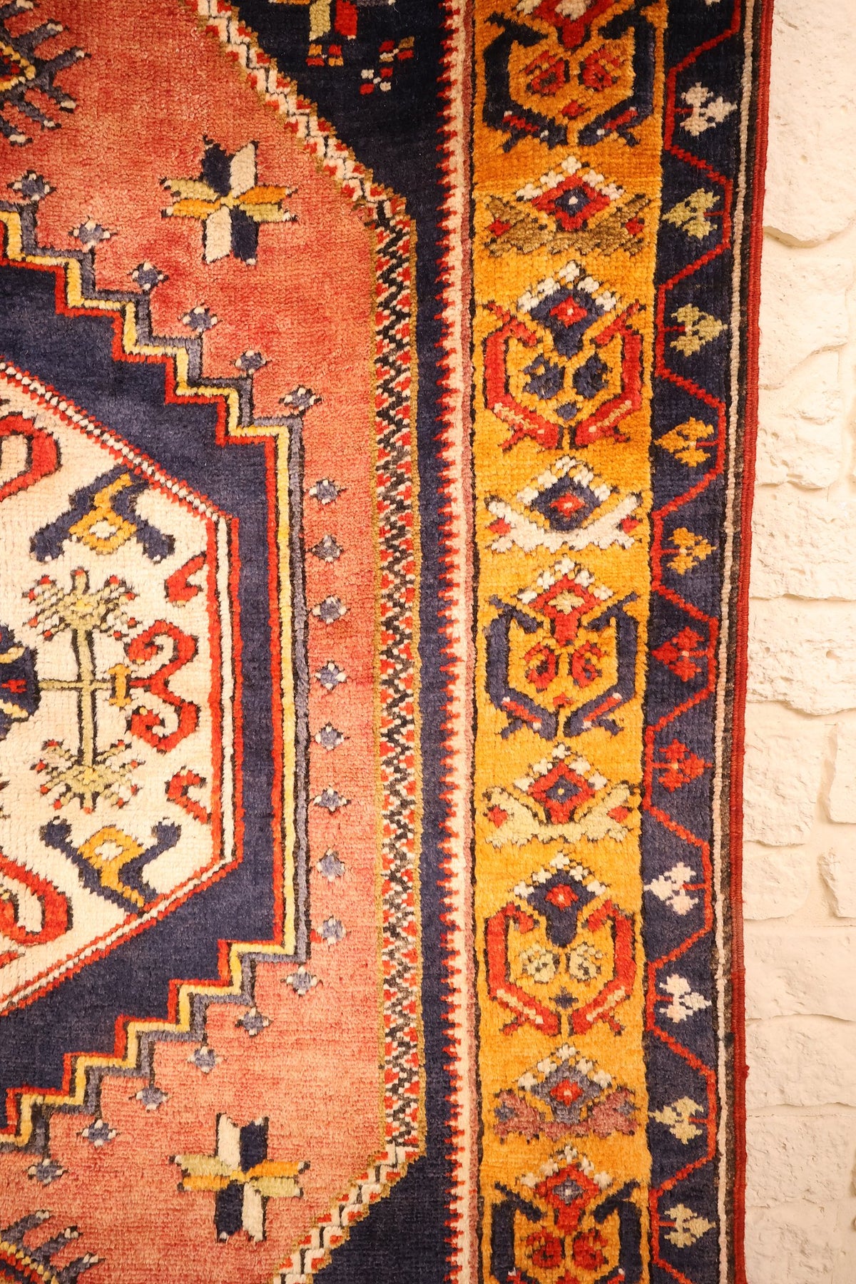 Bordure jaune orangé à palmettes géométriques rouges et bleues du tapis Yahyali