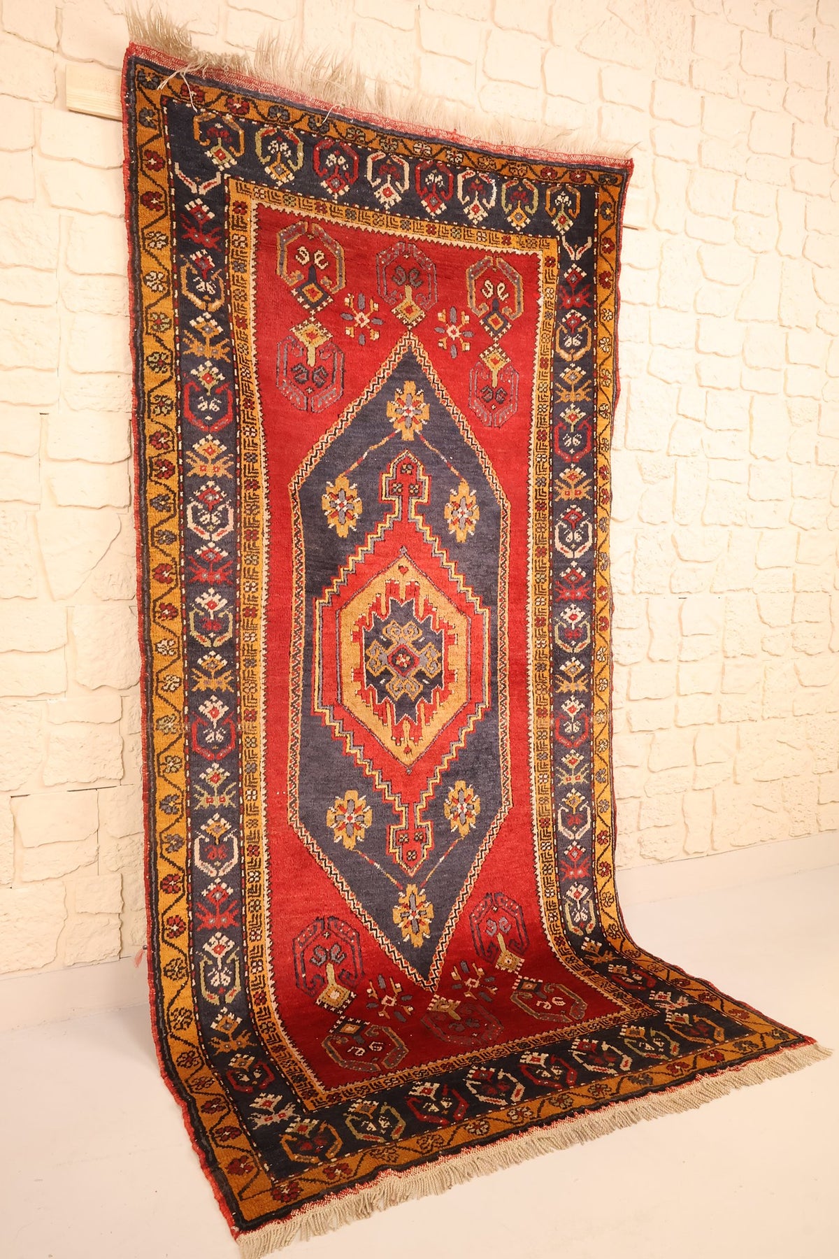 Tapis Yahyali en laine noué à la main, vue de biais montrant le champ rouge et la bordure bleu nuit